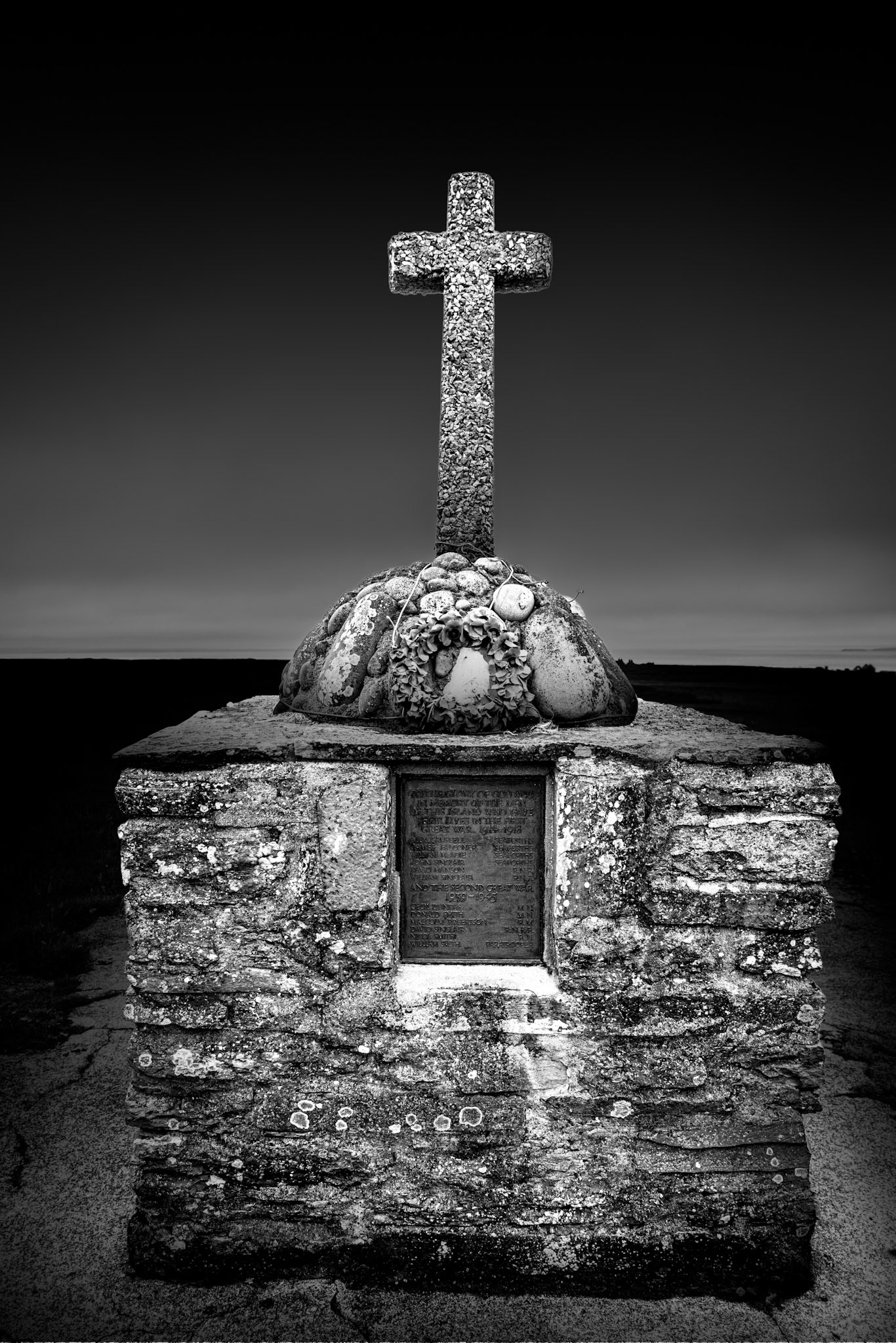 Stroma's war memorial carries perhaps the most explicit reminder that the island's ruins represent individual lives rather than an abstract story of depopulation. The memorial records islanders lost to war and remains cared for despite the disappearance of Stroma's permanent community. When the church closed, the memorial plaque needed a new home and was incorporated into this purpose-built structure; the Simpson family continue to ensure that a wreath is placed here. I photographed the memorial frontally and with very little surrounding distraction, allowing the cross and stonework to emerge against the darkness. Among the abandoned buildings and machinery of Stroma, this is different: a human trace deliberately maintained because remembering the people who once belonged here still matters.Stroma is an ongoing photographic project which I am currently developing.