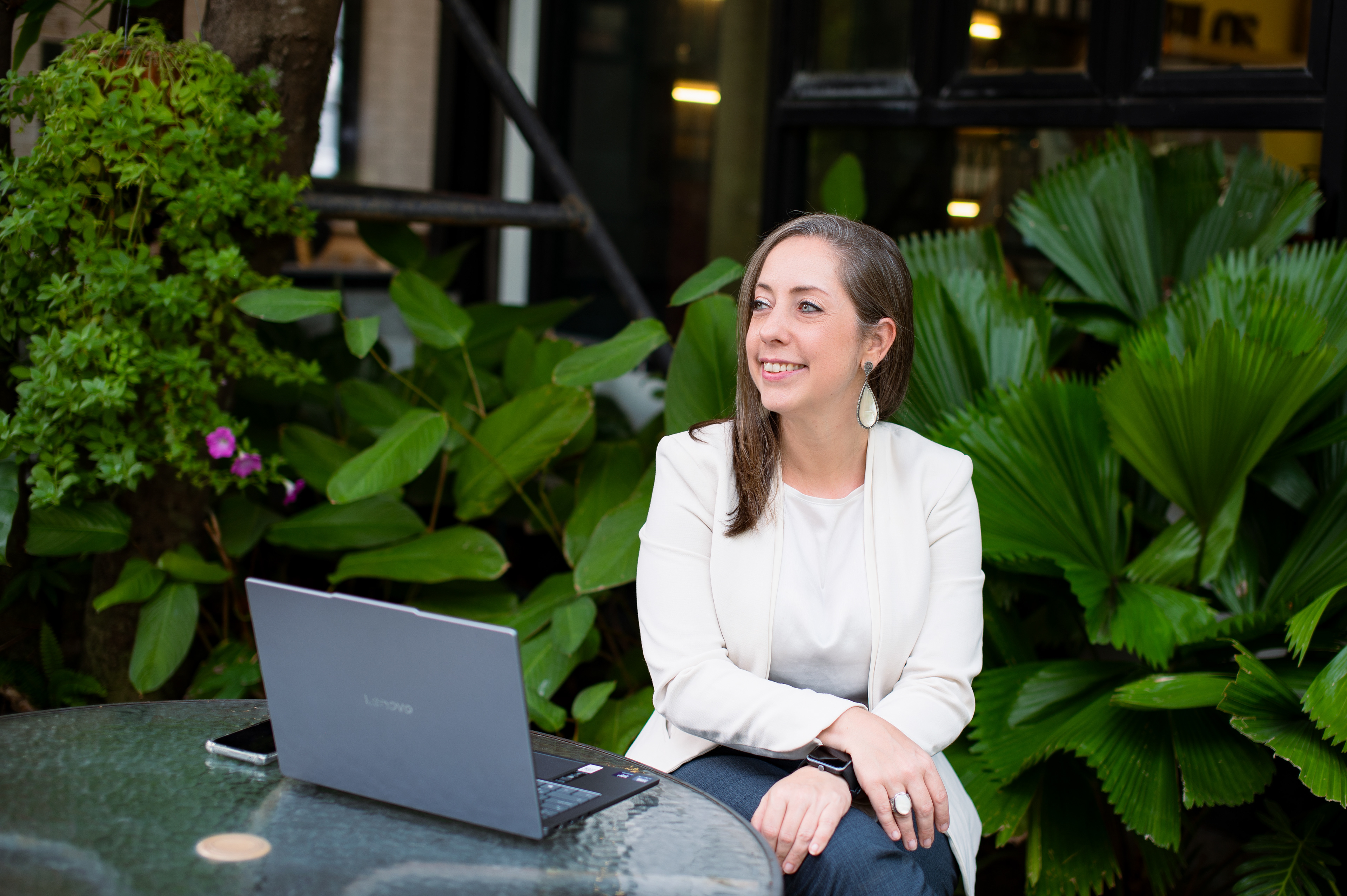 Professional woman sitting with a laptop in a garden setting, personal branding photography by a Bangkok portrait photographer.
