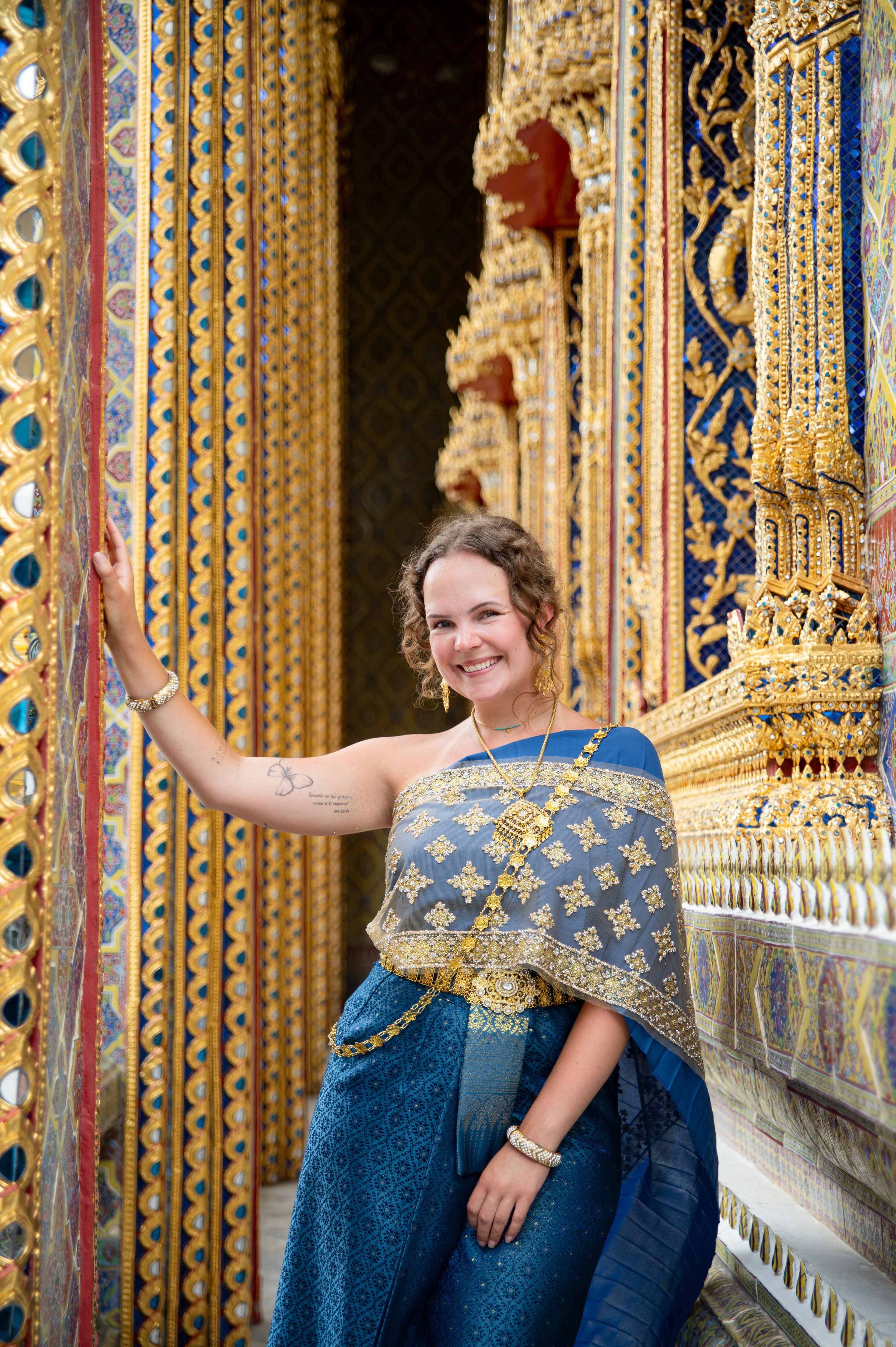 Woman wearing traditional Thai dress standing in front of a temple in Bangkok, photographed by Priscila Medeiros – portrait session in Thailand