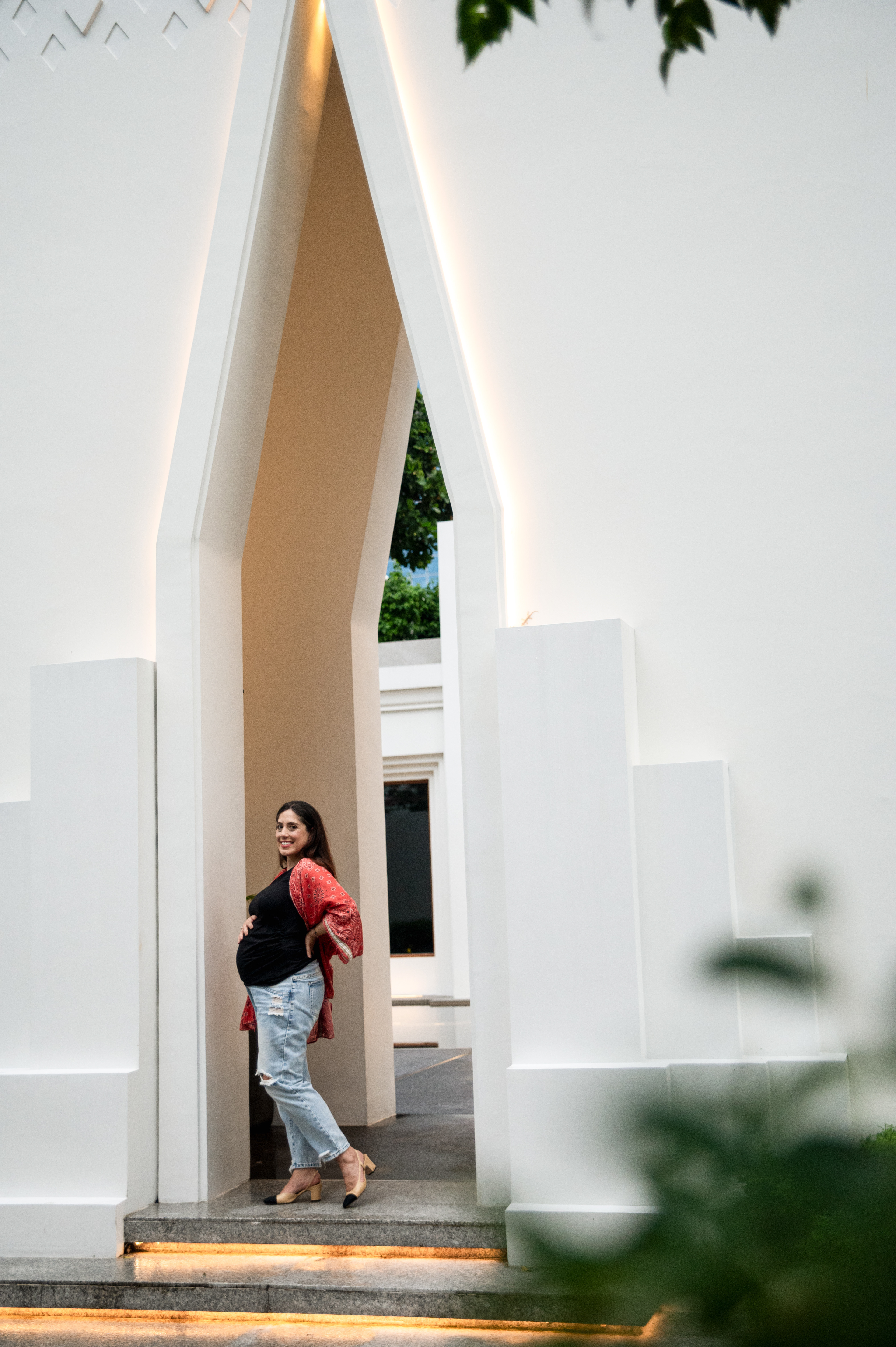 a pregnant woman at the door.  Maternity portrait by Priscila Medeiros Photography in Bangkok