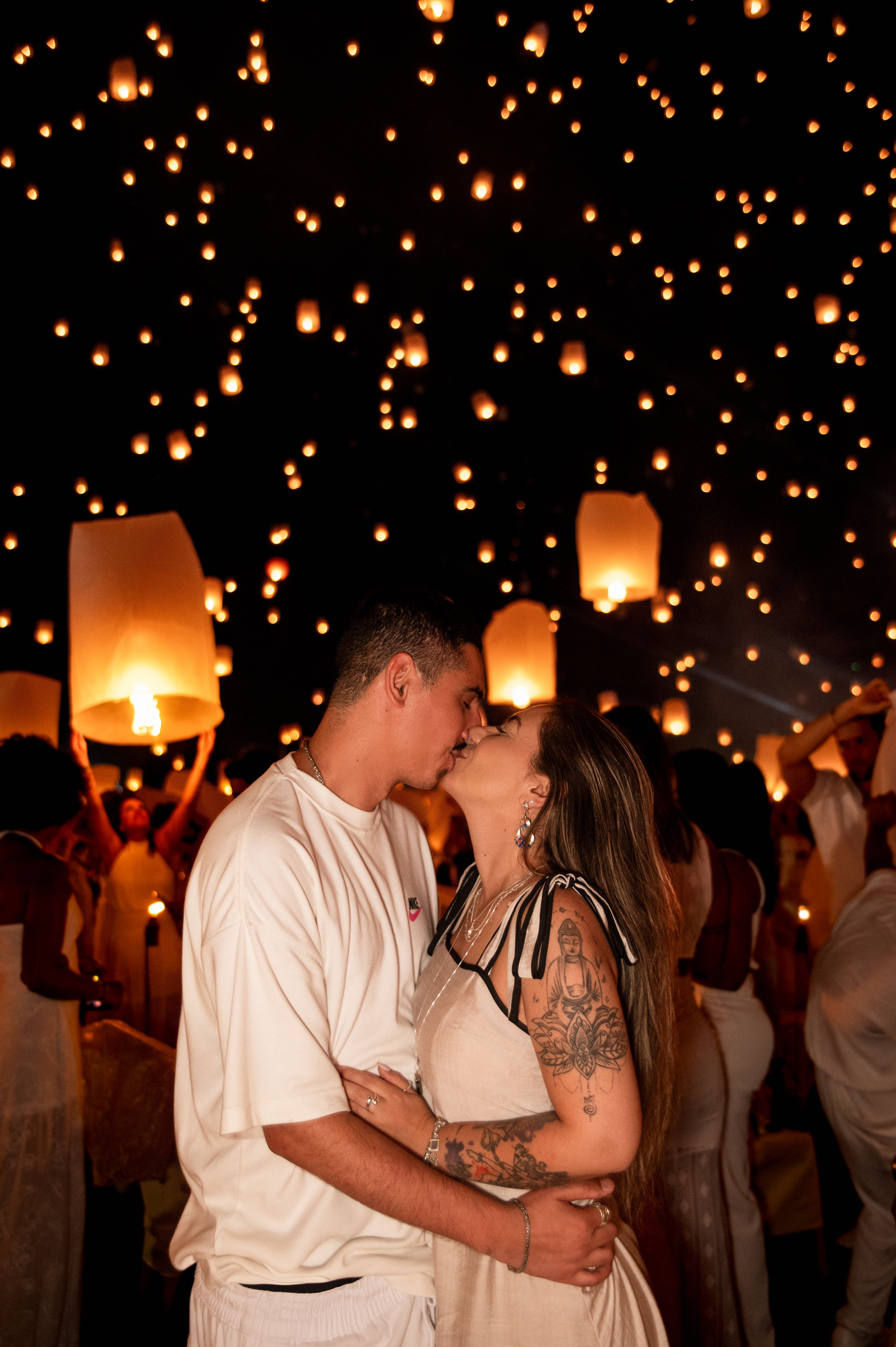 Couple kissing under thousands of floating lanterns during the Yi Peng Festival in Chiang Mai, Thailand; romantic travel photography by a professional lifestyle photographer.