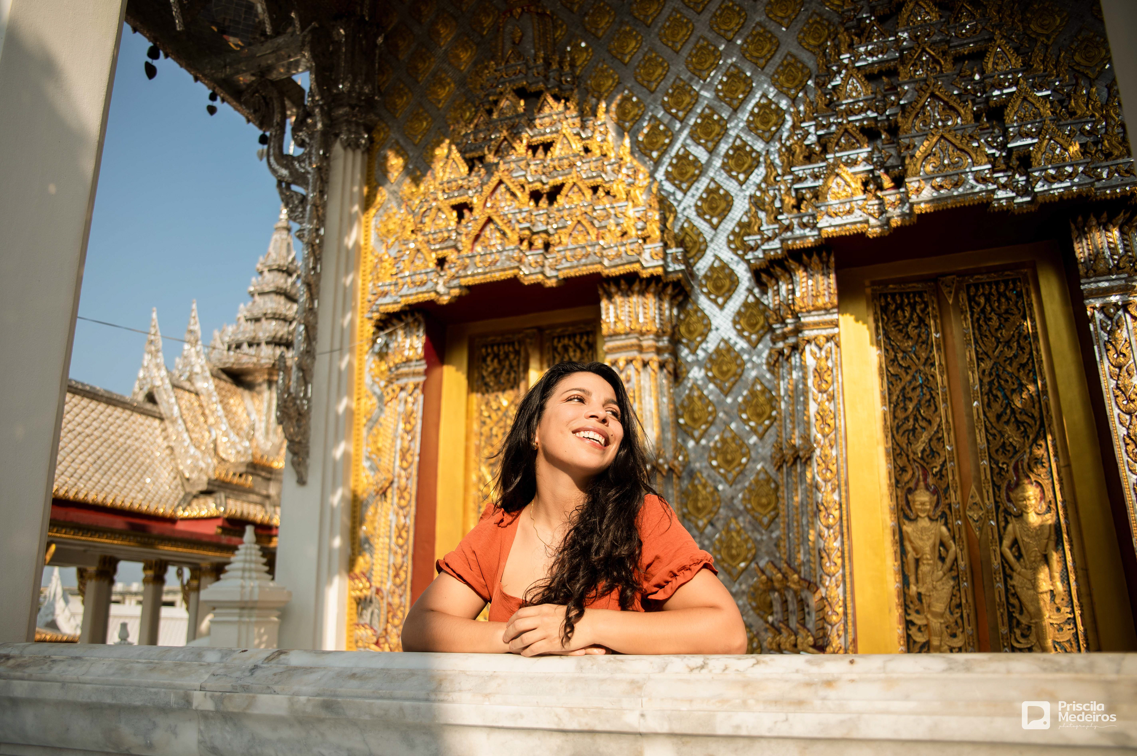 Woman smiling during a professional photoshoot at a beautiful Thai temple in Bangkok.