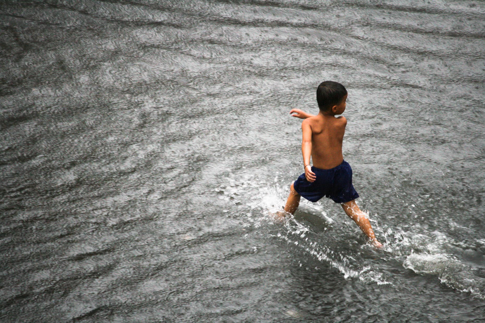 A young boy crossing a flooded street during monsoon rains in September 2008 in Phnom Penh, Cambodia.