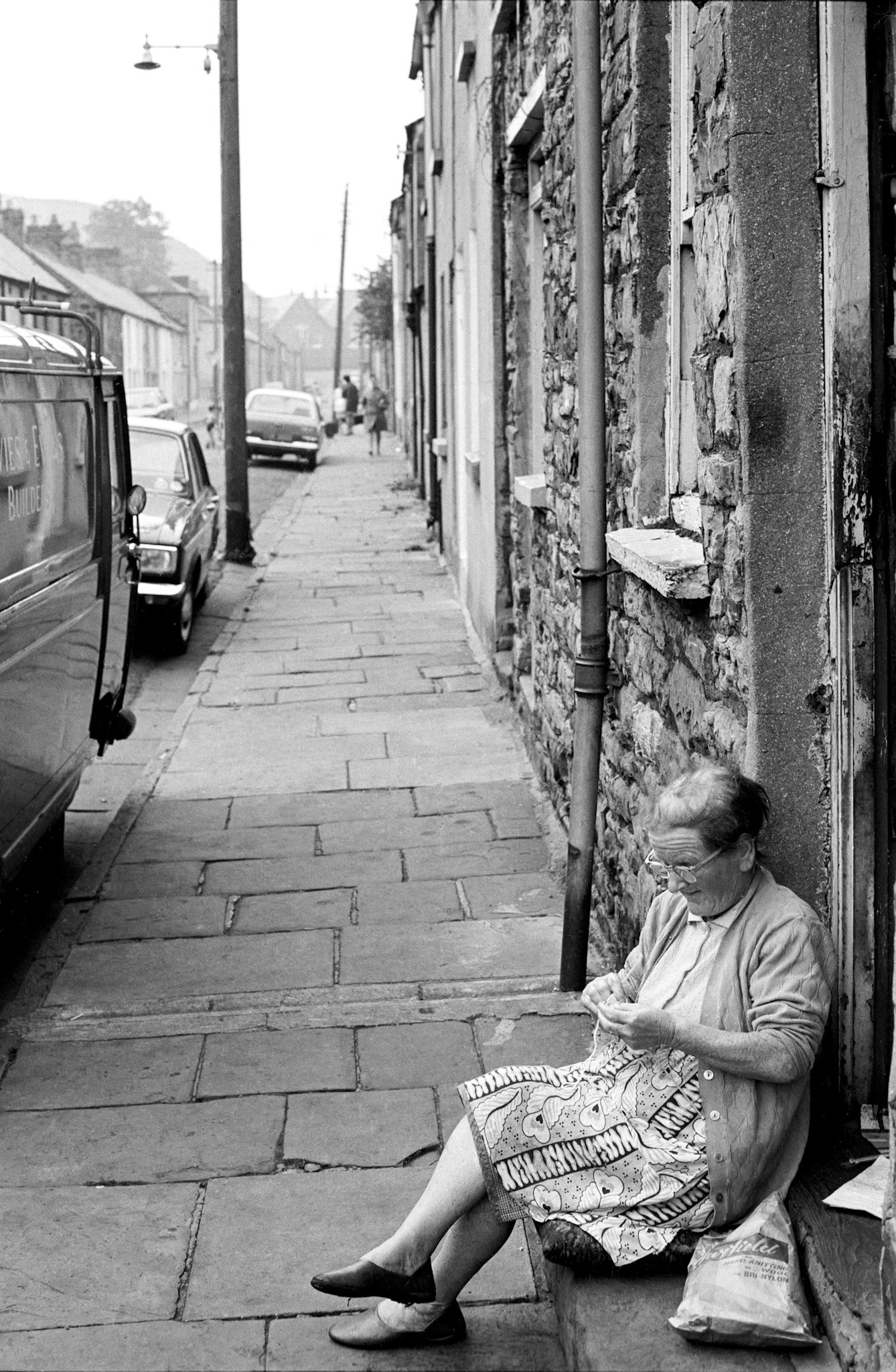 Woman knitting on the doorstep in Georgetown - Women often sat on the doorsteps like this. Georgetown was a close-knit community. It was built to house workers from the Cyfarthfa Ironworks. Not long after this photograph was taken this entire area was bulldozed for redevelopment.
