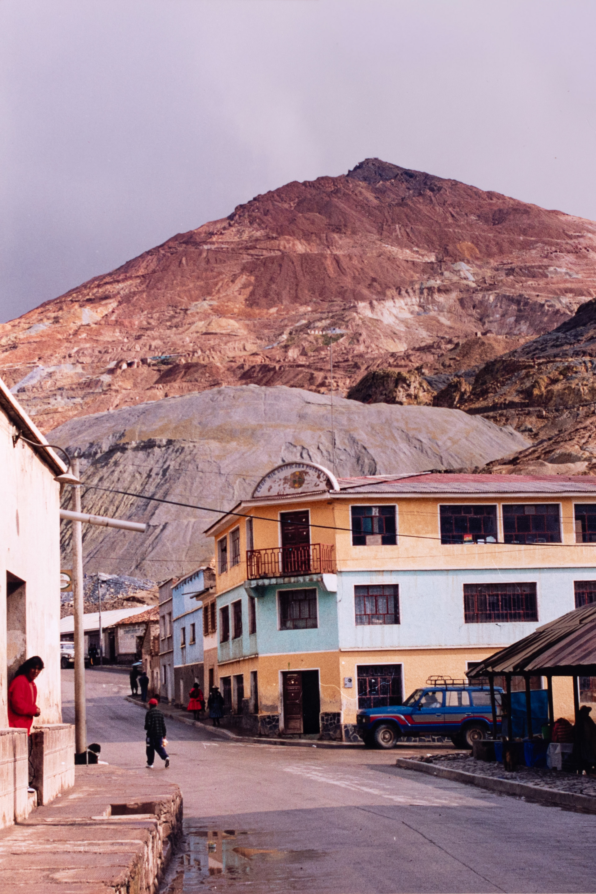 El monumental Cerro Rico, desde cuyas entrañas salieron millones de toneladas de plata rumbo a Europa, a costa del sacrificio del pueblo indígena. Abajo, el edificio de la Cooperativa Minera del Potosí, que agrupa a los trabajadores que siguen explotando la mina.
