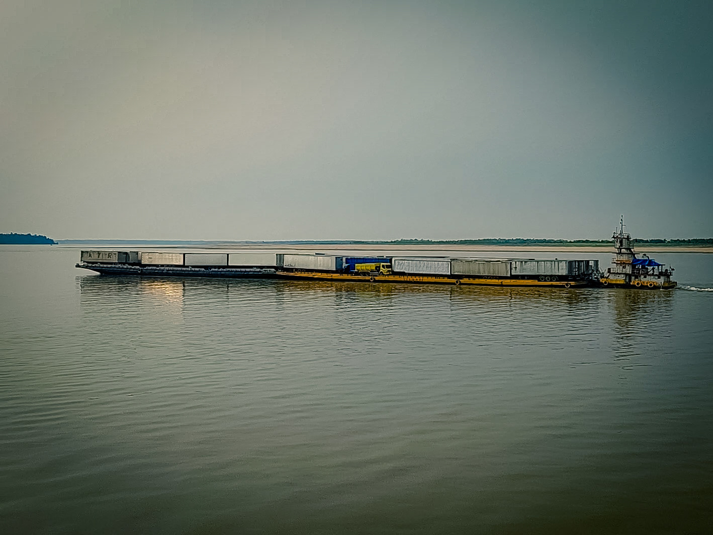 Una barcaza transportadora de trailers y camiones avanza por el río.