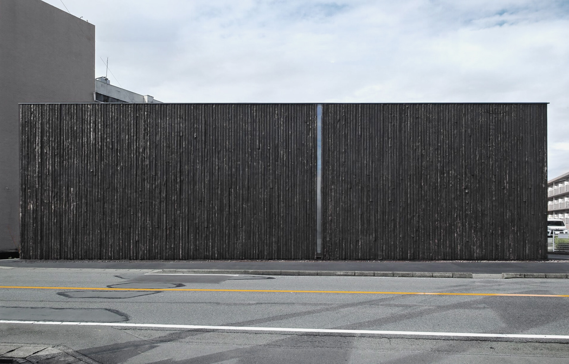 壁面に間伐材が用いられた「幸ハウス」の建築と道路が映った写真