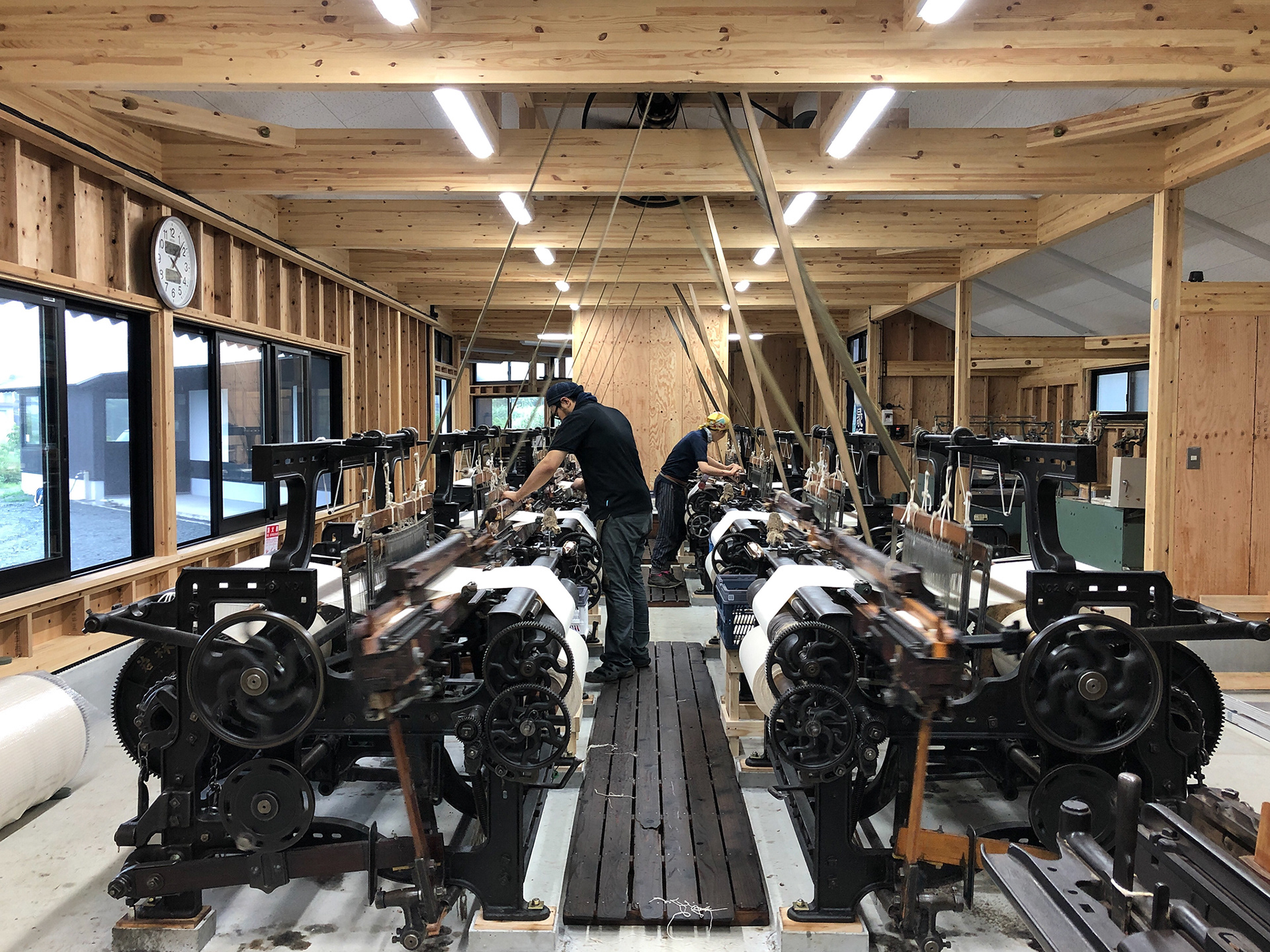 大きな機械のある工房で作業をする男性二人