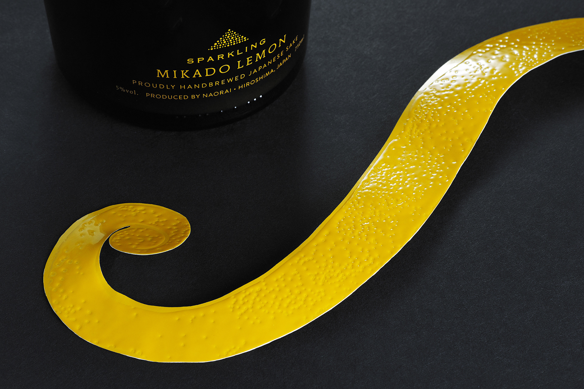 黒い空間に置かれた「MIKADO LEMON」のボトルとレモンの皮を再現したラベル