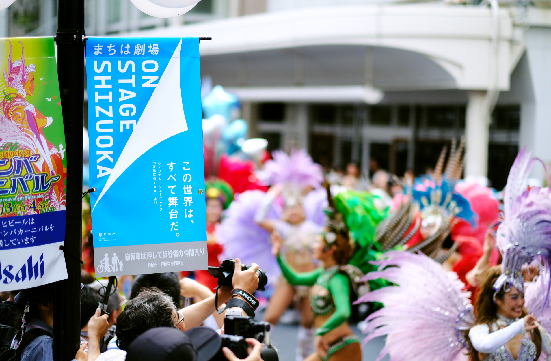 「ON STAGE SHIZUOKA」のフラッグ広告とサンバを踊る複数の女性が写った写真