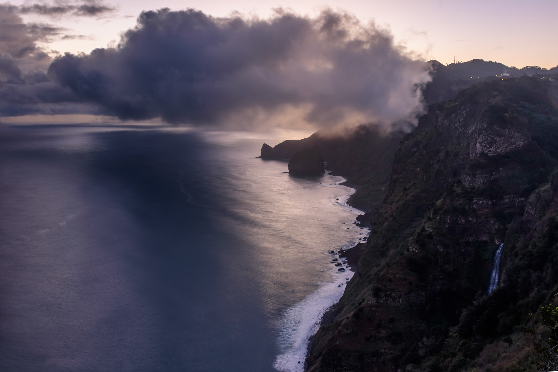One day in December I was lucky to be the first person to witness the sunrise in Madeira, from its highest pick  - Pico Ruivo, 1862 m. Reaching up before 7 am wasn’t necessarily hard, however, the wind and the low temperatures added a bit of challenge to the climb. This picture was taken shortly before sunrise, when the little tow of Santana (down) was still asleep under a dense cover of clouds, waiting for a new day to start.