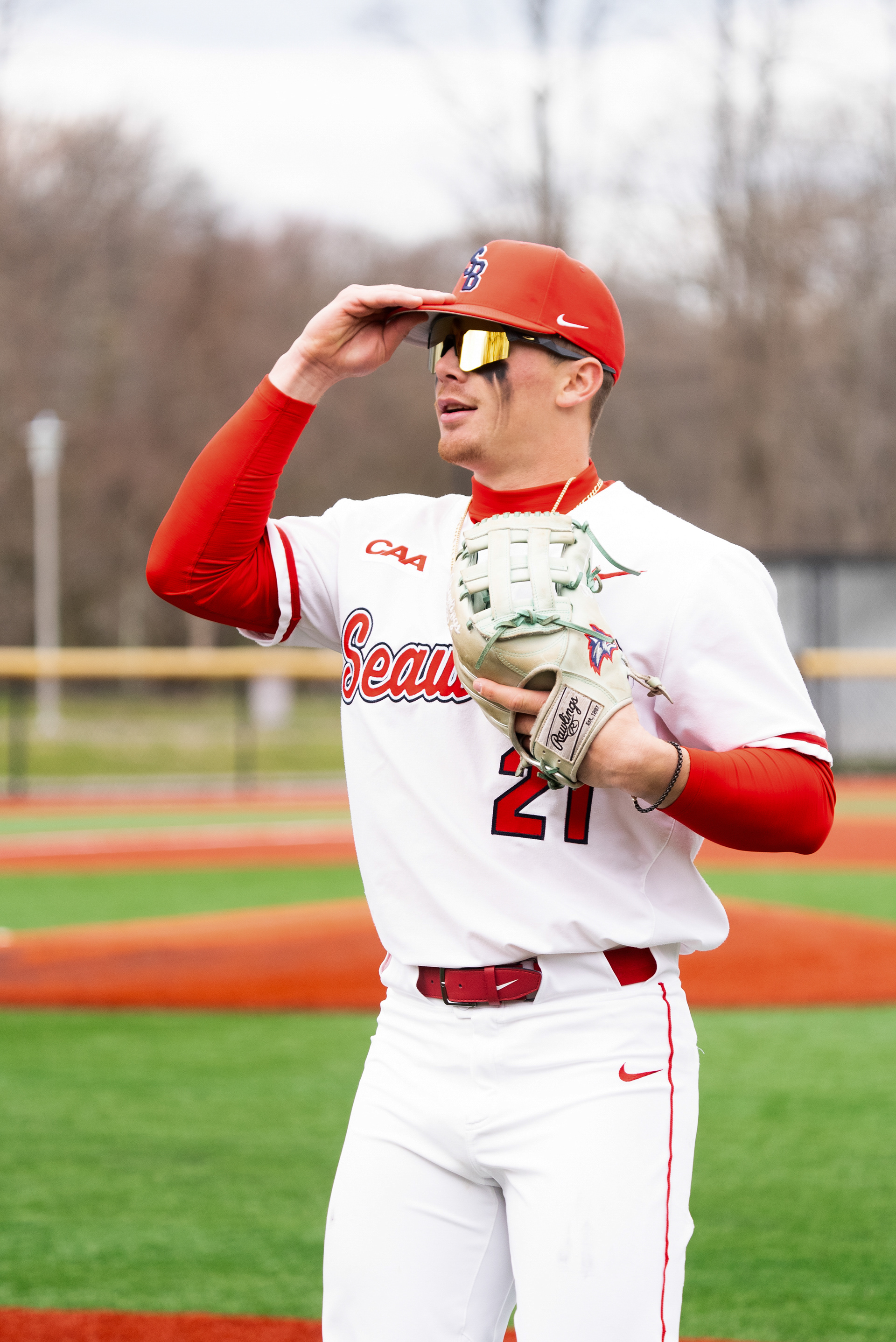 Matt Brown-Eiring putting his cap on as he talks to a teammate before heading out onto the field - Stony Brook, NY 4/5/2024
