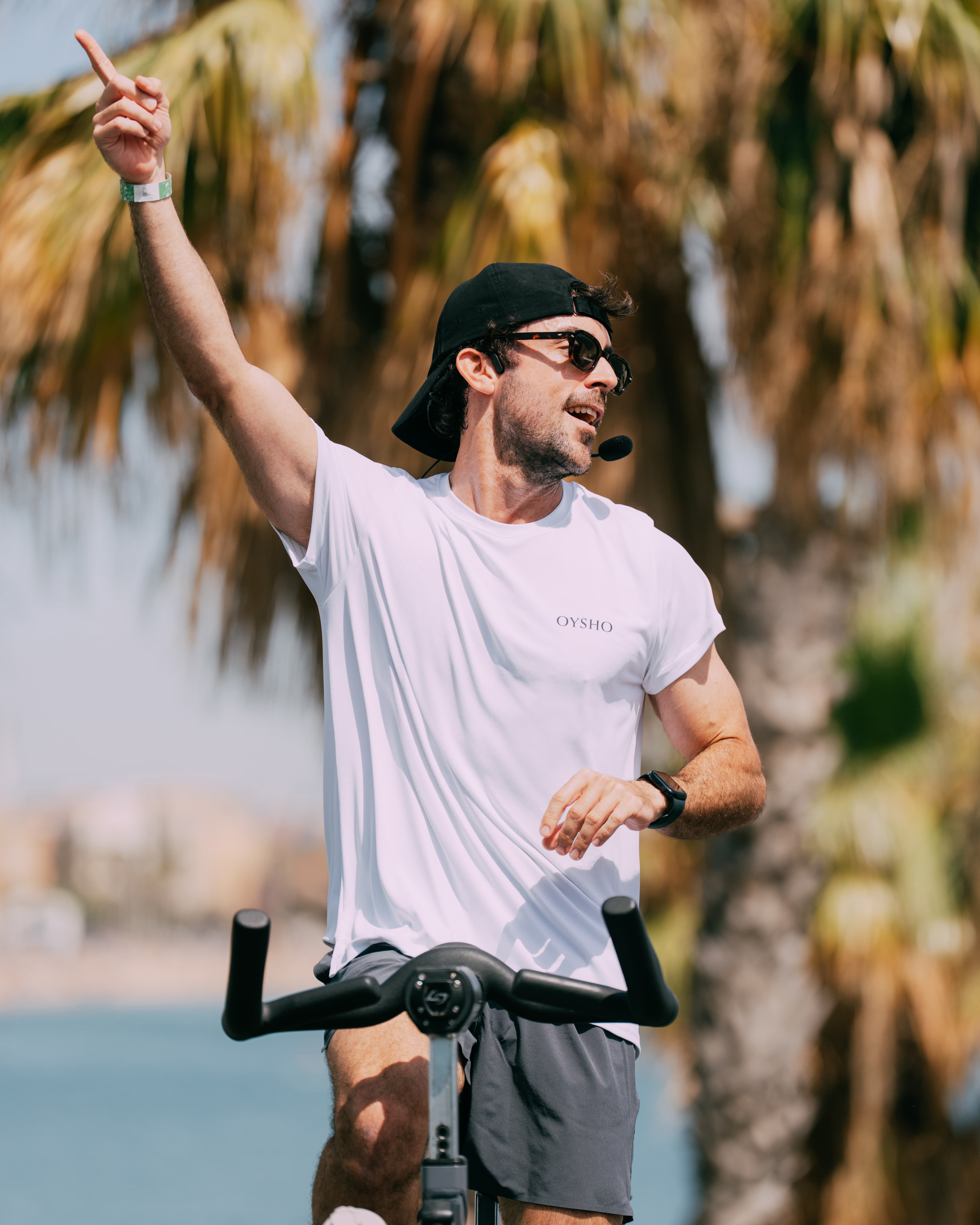 Instructor pointing up under palm trees, sports event photography