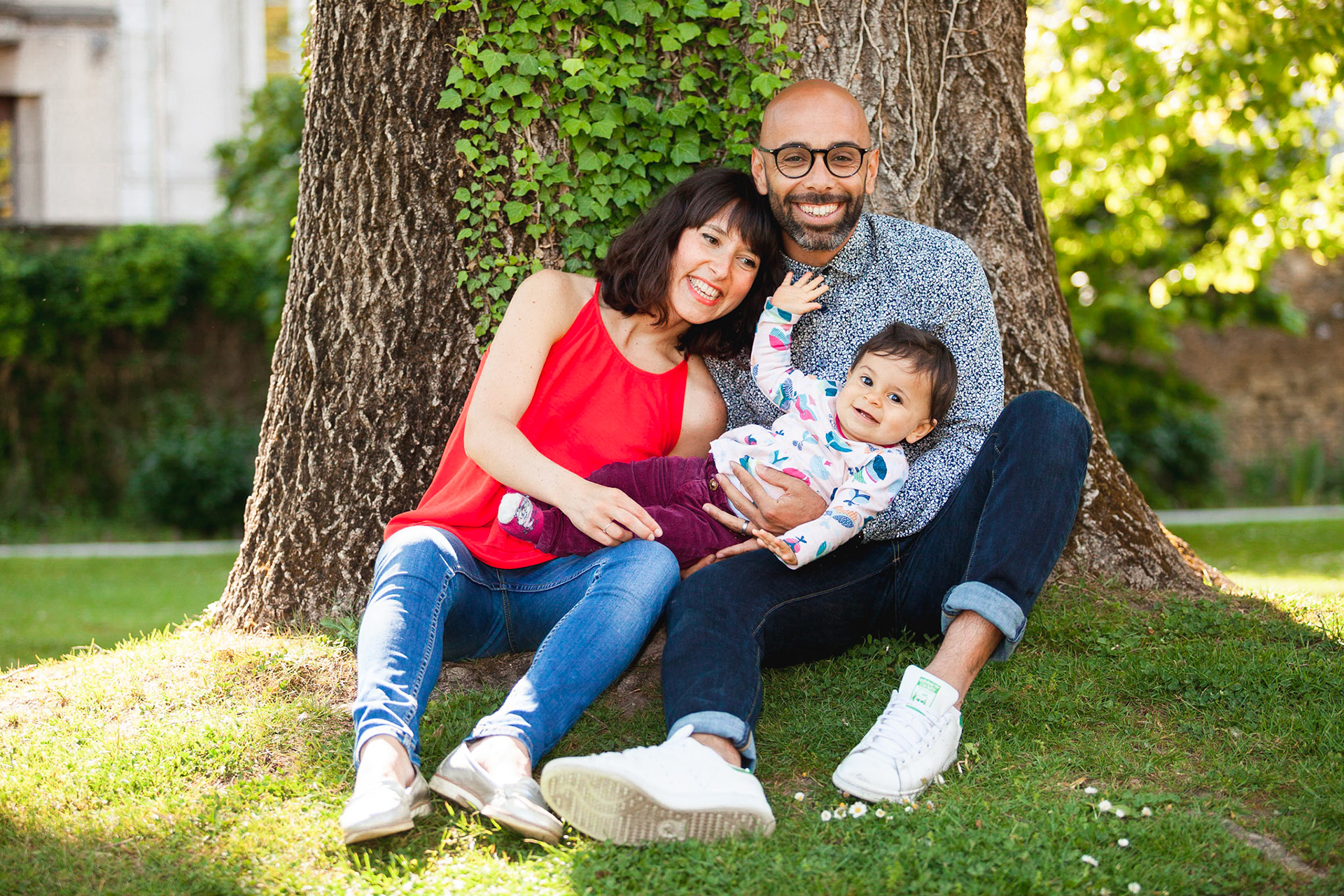 Famille heureuse assise contre un arbre. Photo couleur.