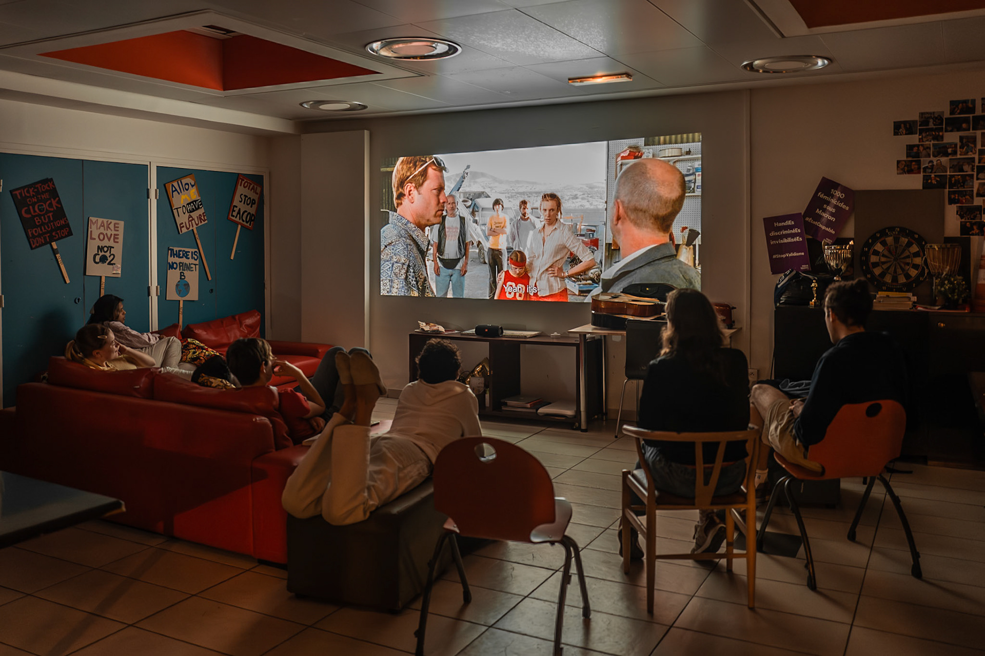 A group of students gathers in the main hall to watch the film “Little Miss Sunshine” projected on a large screen. The shared screening creates a communal atmosphere, turning the residence into a cozy cinema space. The scene captures a simple but meaningful moment of student life, centered on collective enjoyment and togetherness. Picture taken the 2026-05-03©Aurora Ghigino