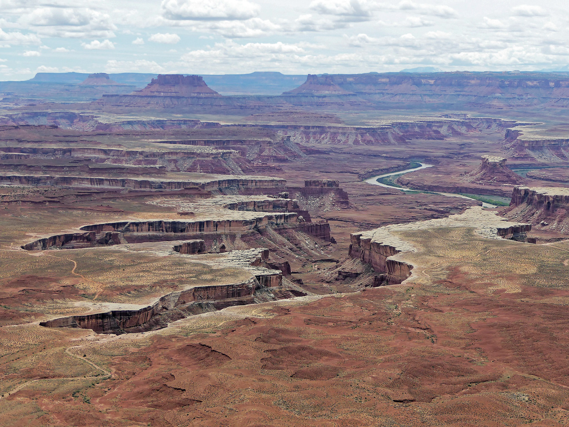 View over to the Maze from the Green River Overlook, Island in the Sky.  In the distance are Elaterite and Ekker Buttes. To the right of the river is the Turks Head and in the foreground the White Rim Trail. On the horizon to the right are the Henry Mountains.