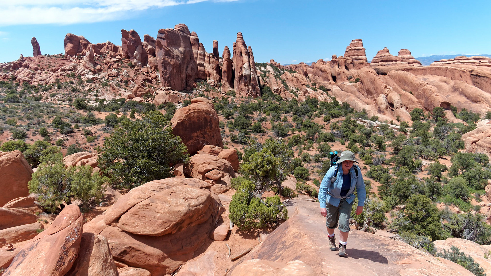 Jenny climbing the fin up from the Double O Arch area on the Devils Garden Trail, Arches National Park. The Primitive Trail joins from the right of the picture and the trail continues to to the Dark Angel on the far left,
