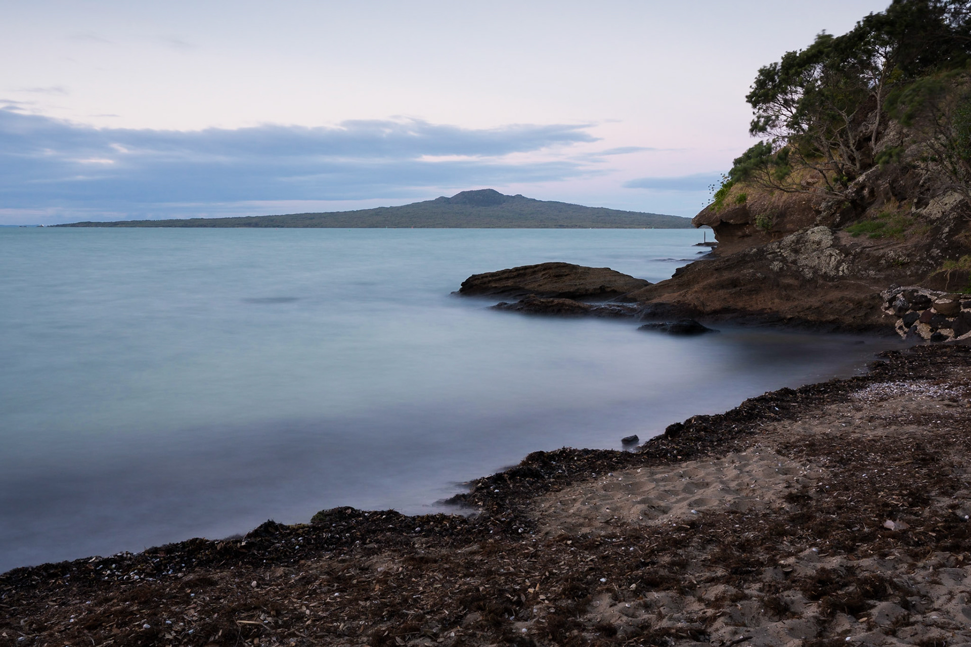 A long exposure photo of Rangitoto Island seen from Chelthenham Beach.