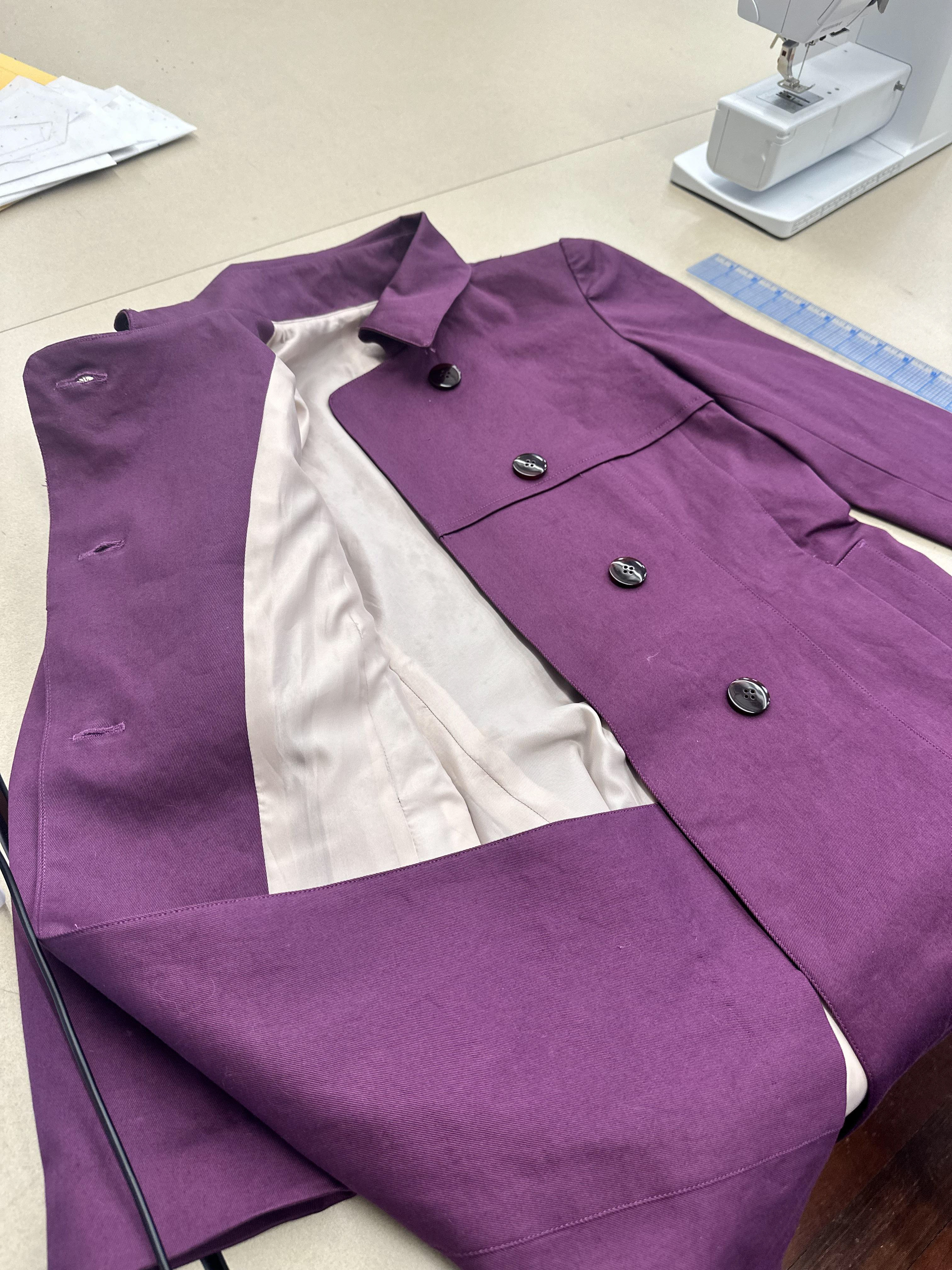 The trench coat features a a double-breasted button closure.