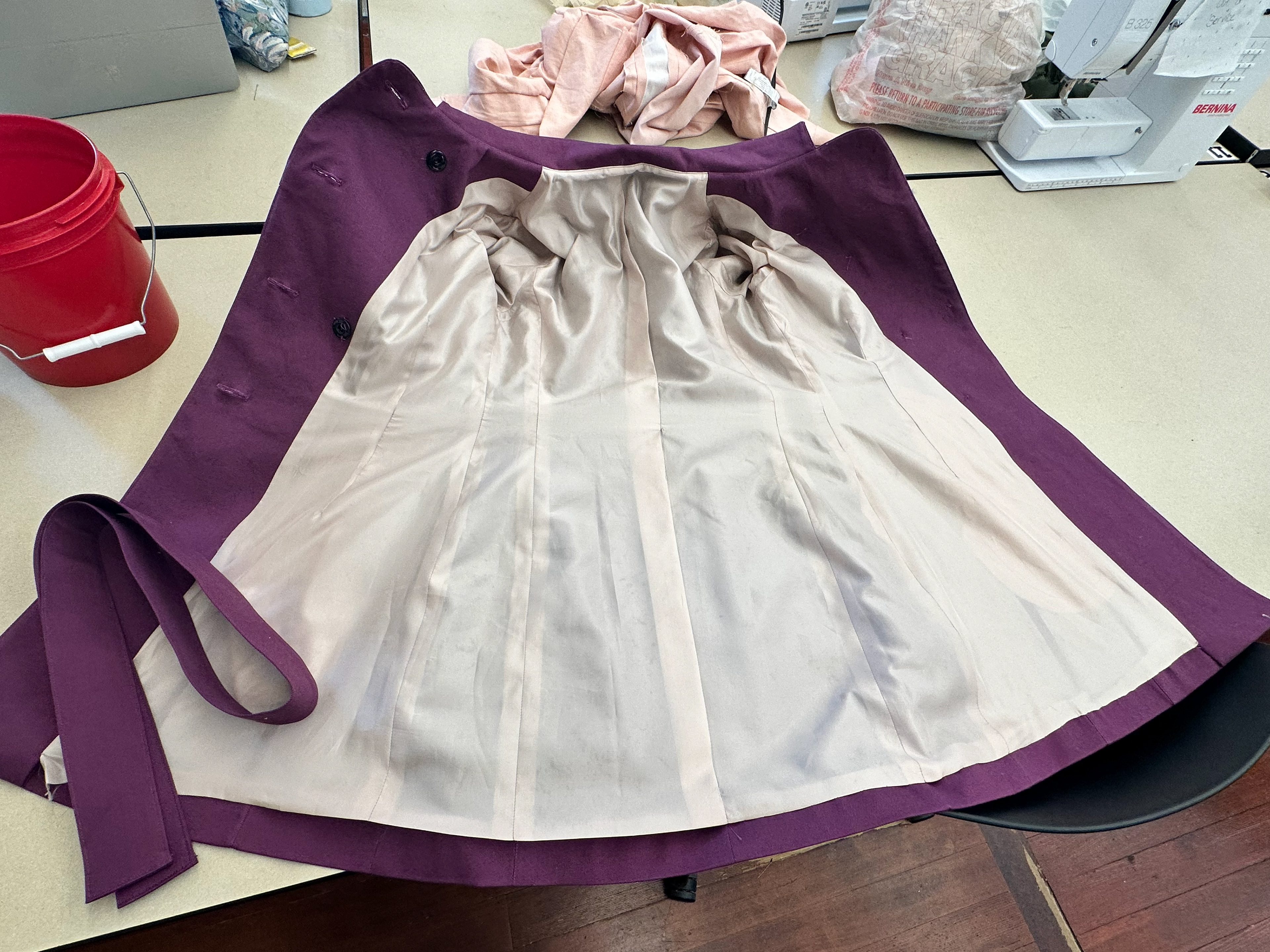 The trench coat is lined with a light pink acetate lining.