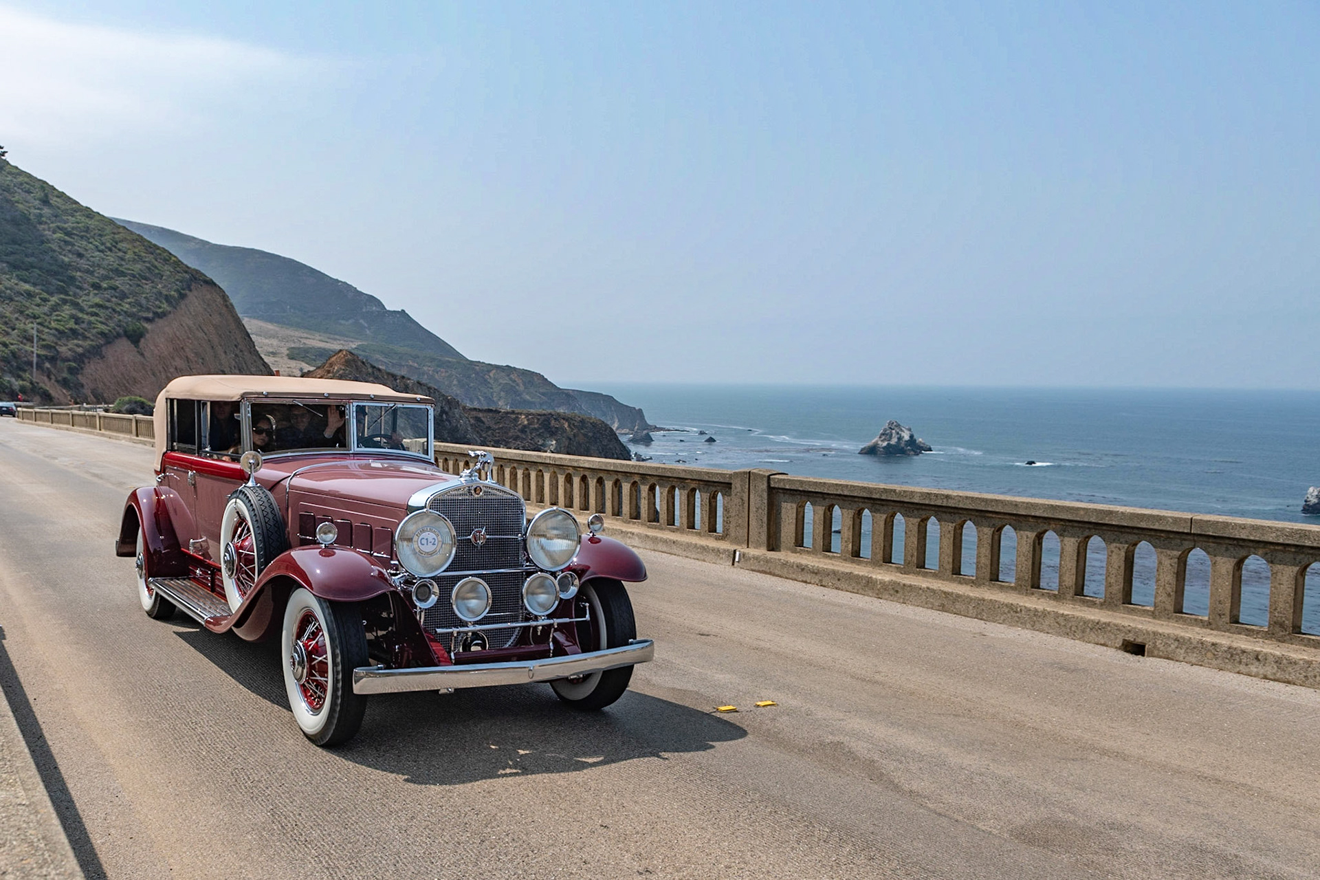 In 1930, when the world and US economies were collapsing, Cadillac took the brave step of introducing their new, and expensive, V-16 engine. This 1931 452A V-16 All-Weather Phaeton with coachwork by Fleetwood, Cadillac’s in-house body builder, is finished in the striking color combination of rose red over dark red fenders. The body features several interesting details, such as a vee “Pennsylvania windshield” and a glass division between the driver and the passenger compartments. It is also fitted with dual side mount spares topped with correct Cadillac mirrors, twin Pilot Ray spot lamps, a radiator stone shield, the goddess radiator mascot, and a matching dark-red trunk that has been restored to match the car.