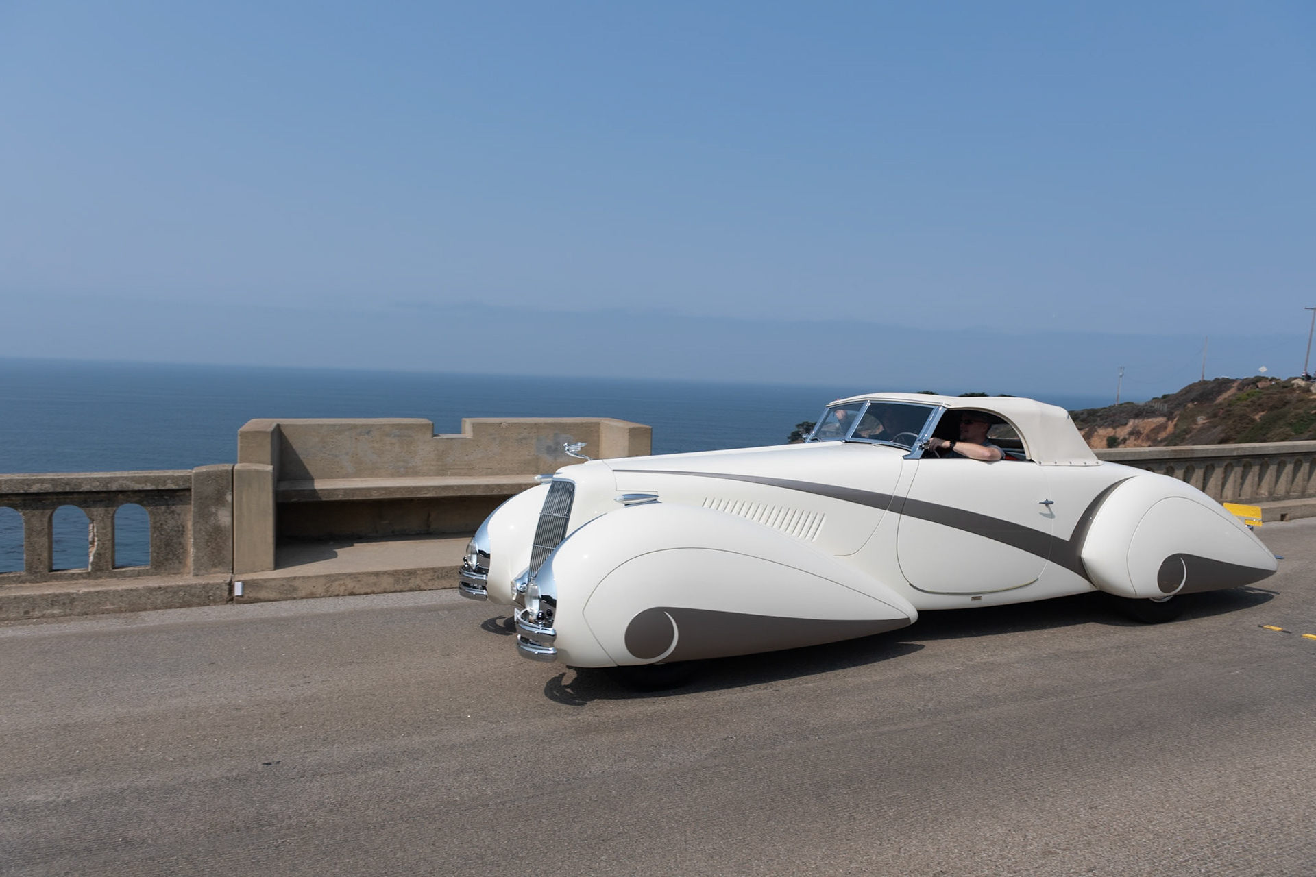 In 1937 Cadillac built fifty of their most expensive Series 90 V-16 chassis, and all but two were bodied in-house by Fleetwood. This chassis was delivered to Lausanne, Switzerland, to be bodied by Carrosserie Hartmann per an order by local resident Philippe Barraud, a wealthy playboy of the 1930s. Barraud wanted an outrageous, bespoke automobile to suit his stylish lifestyle. Stretching 22 feet in length, the car was designed in the sweeping cabriolet style of the Delahaye built by Figoni &amp; Falaschi for the 1936 Paris Auto Salon. The car soon suffered several accidents, possibly because its size was unsuitable for small European roads, and it was permanently parked in 1939. Then it was all but abandoned until the summer of 1968 when a second owner acquired it for just $925. Over the following 50 years it changed hands many times and gained several nonoriginal embellishments, but this unique and imposing Cadillac V-16 now has been meticulously restored to its original configuration and its original off-white paintwork with distinctive gray body stripe and fender skirts for its debut at the Pebble Beach Concours d’Elegance.