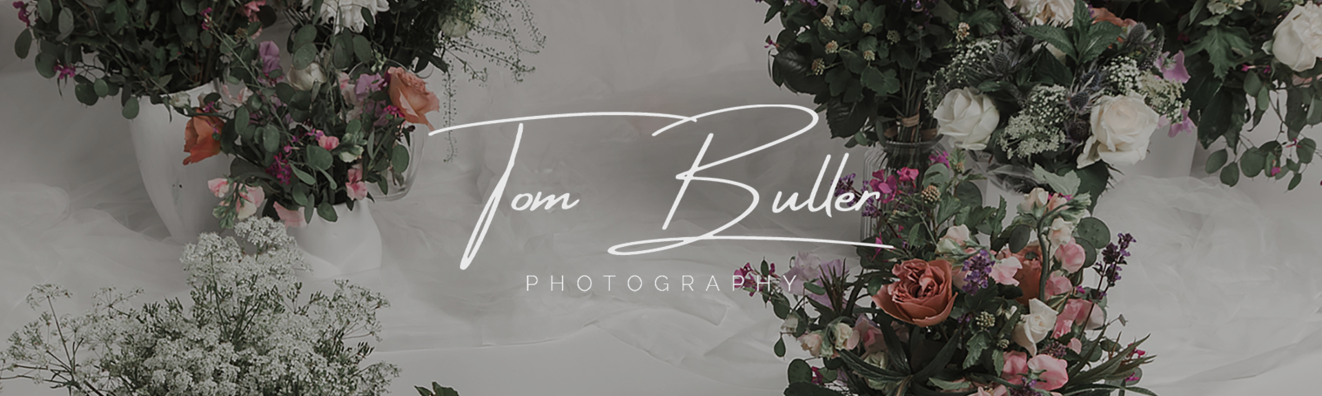 A footer image for the Contact page. It shows a floral arrangement on soft white fabric.