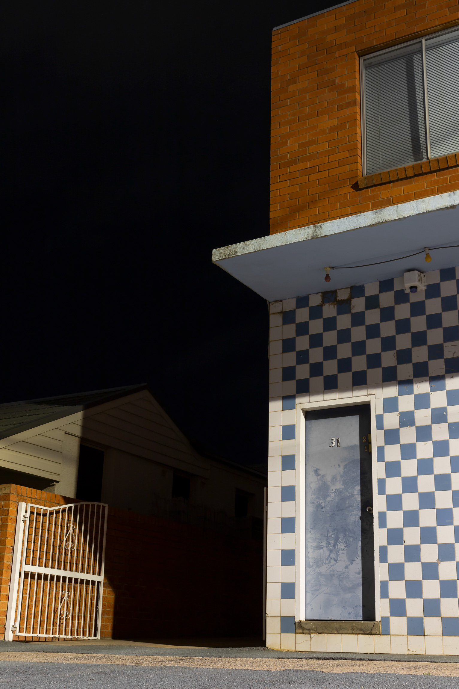 night photo of a building with blue and white chequered tiles