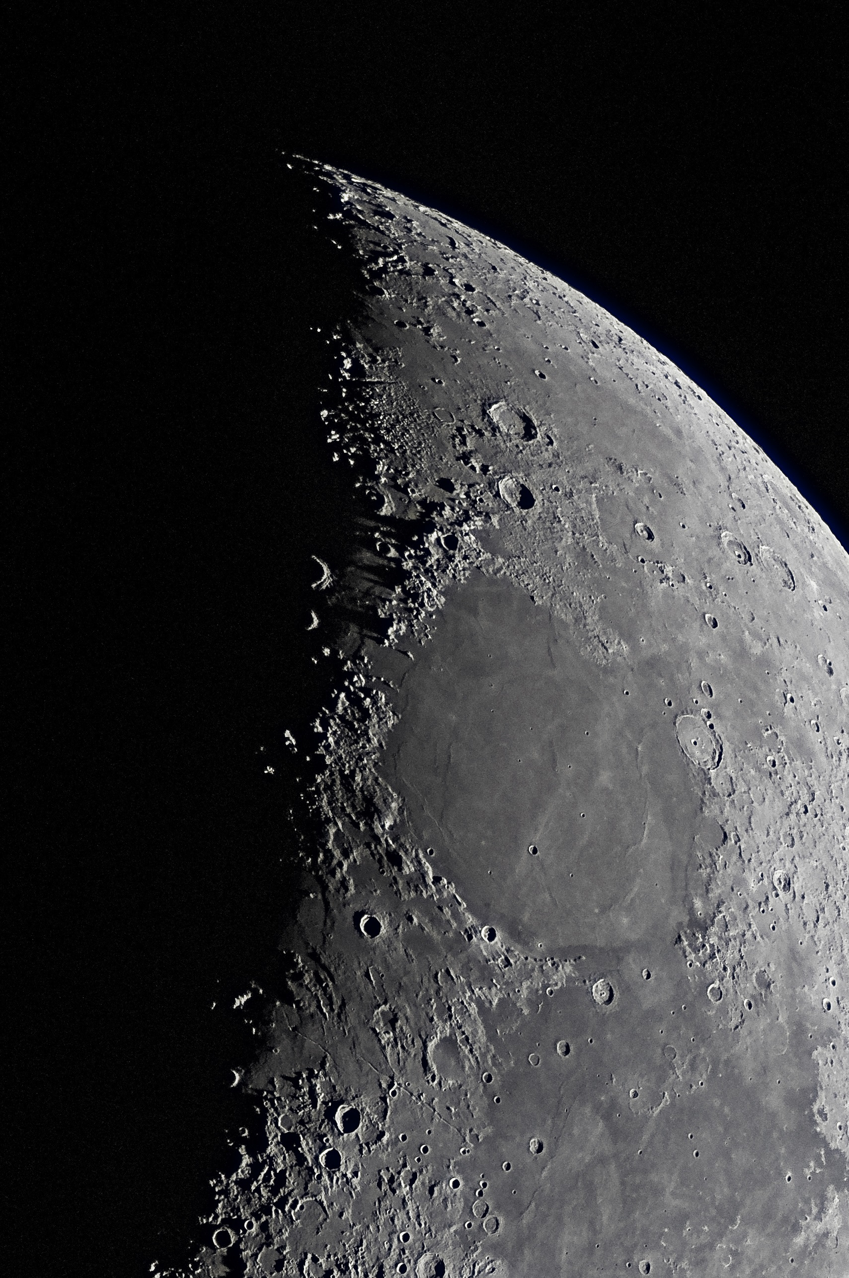 Northern Lunar Pole, Seas of Cold, Serenity, and Tranquility The smooth patch of mare in shadow just below the Northern Pole is the Alpine Valley, which leads eastward (right) into the highest-latitude region of lunar basalts, the Sea of Cold. Just to the south, two large craters, Aristotle (top) and Eudoxus, blemish the landscape vertically . To their west, (left) the Alps Mountains follow downward along the day/night line, or terminator.  Moving southward along the terminator leads to the Caucasus Mountains that border the upper rim of the Sea of Serenity. The range casts long shadows westward into the the Sea of Rains, which is almost entirely in shadow.  Continuing down along the terminator, the Aristillus and Autolycus craters are in half-shadow. Just below them, the Apennine Mountains emerge from the terminator and border the western edge of the Sea of Serinity.