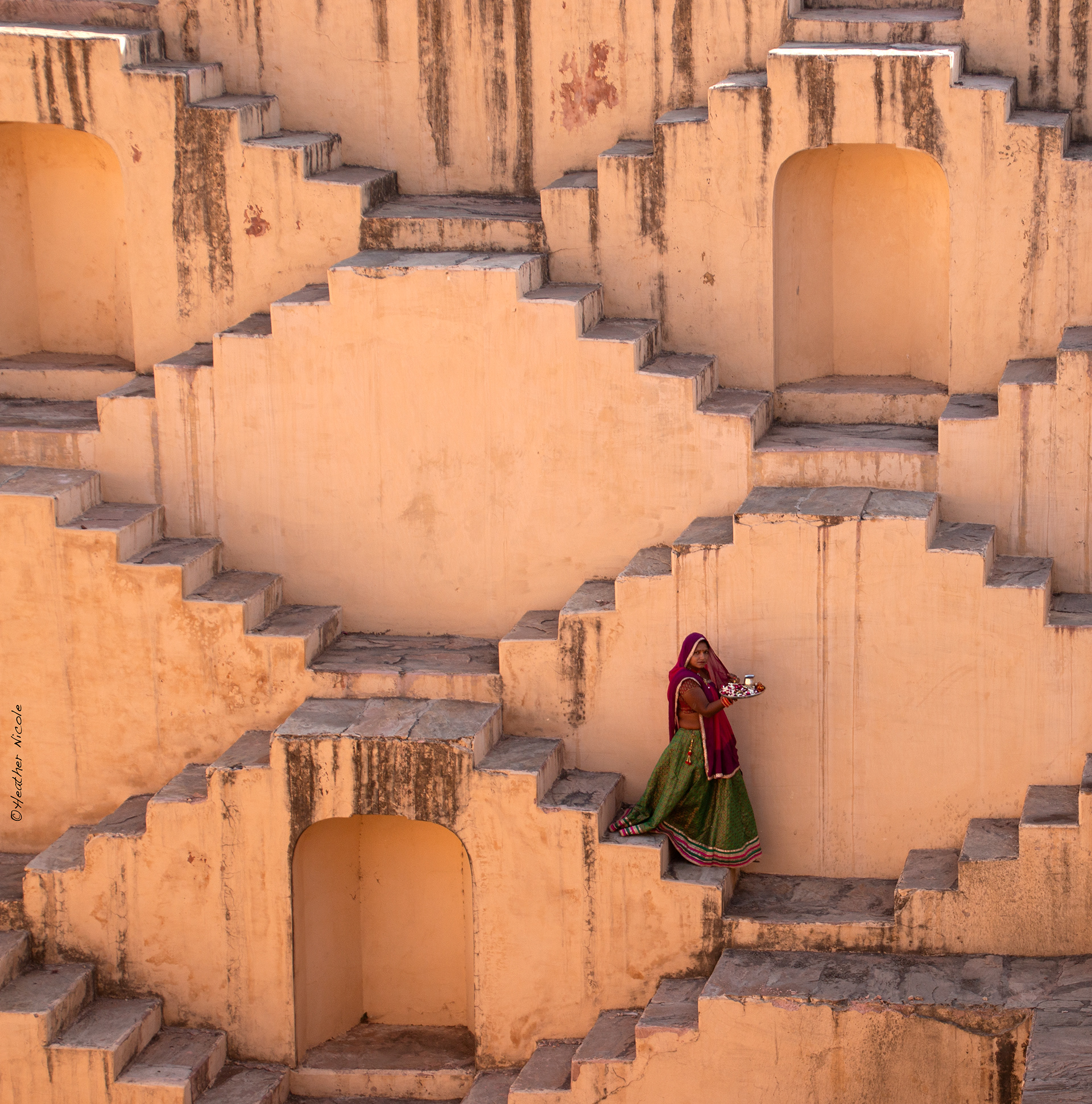 An Indian woman in a traditional sari walks down the treacherous steps of an ancient step-well.