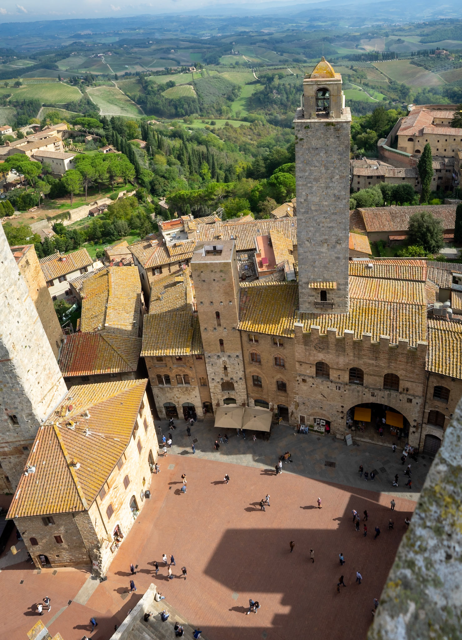 View of Piazza dell Duomo and the green fields on the horizon, San Gimignano