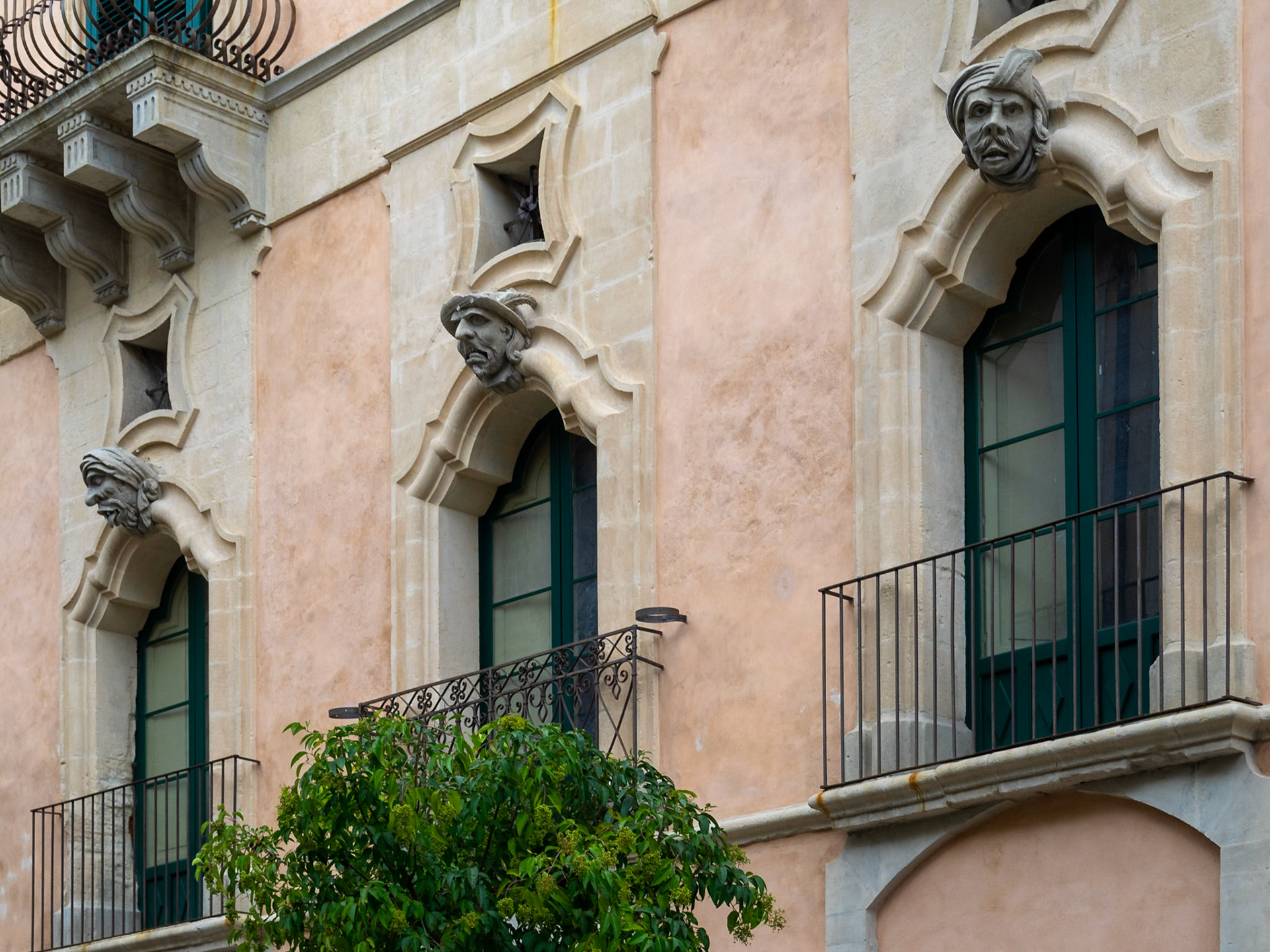 Palazzo Bertini facade detail with stone carved heads over the balconies doors