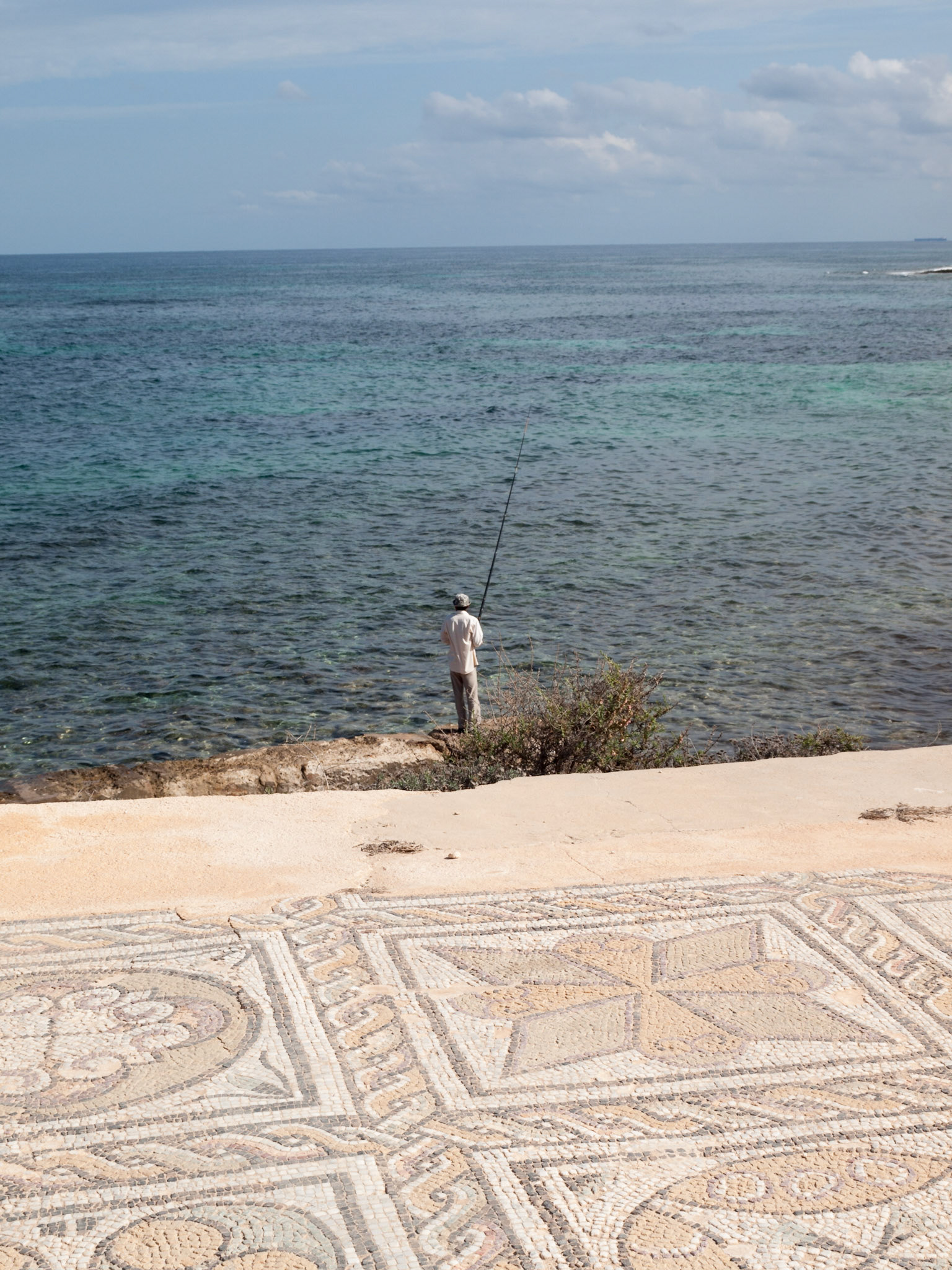 Mosaic of the Roman ruins of the Baths of Oceanus in Sabratha with sea and fisherman in background