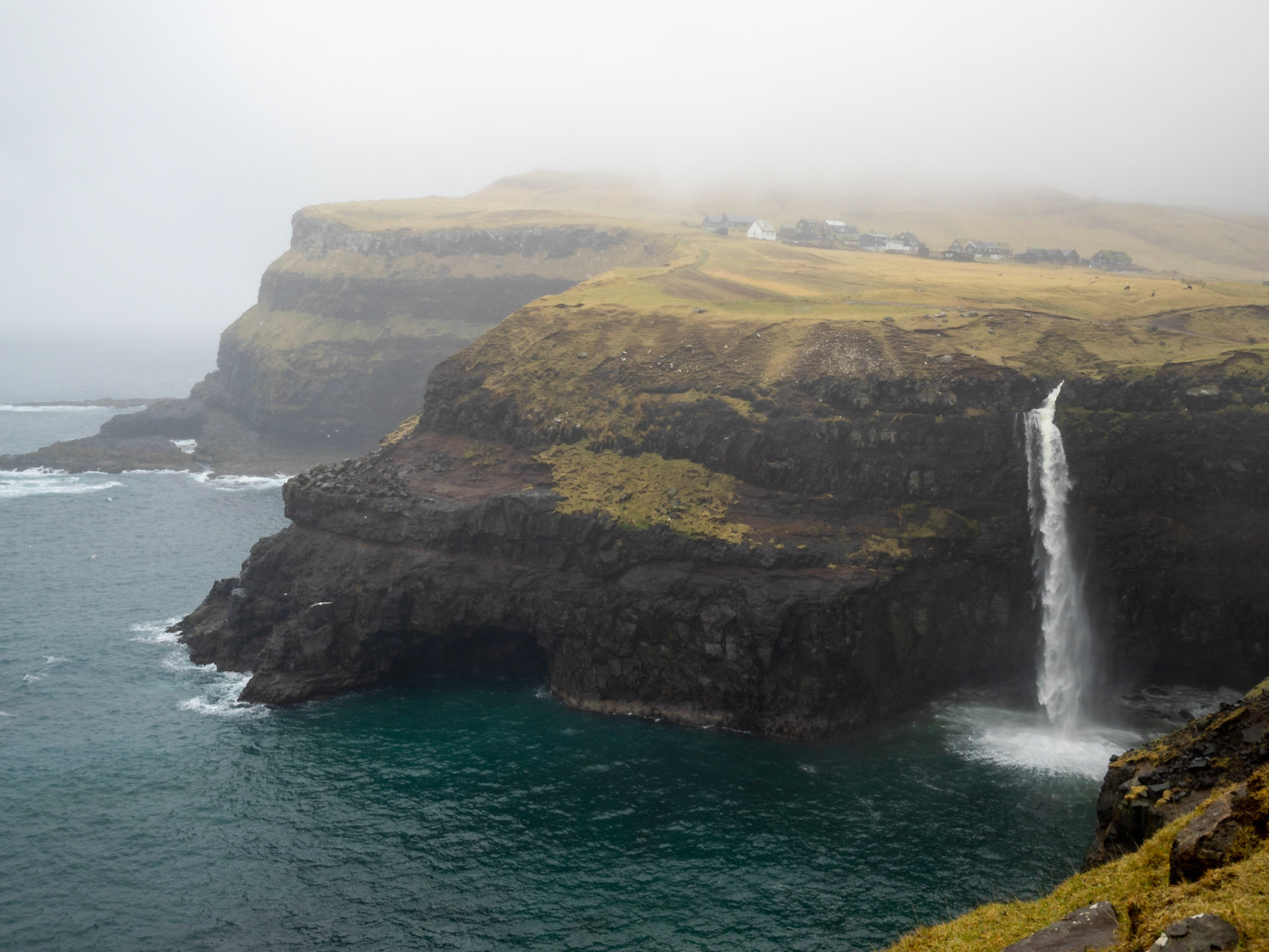 Múlafossur waterfall emptying from the cliff top to the ocean