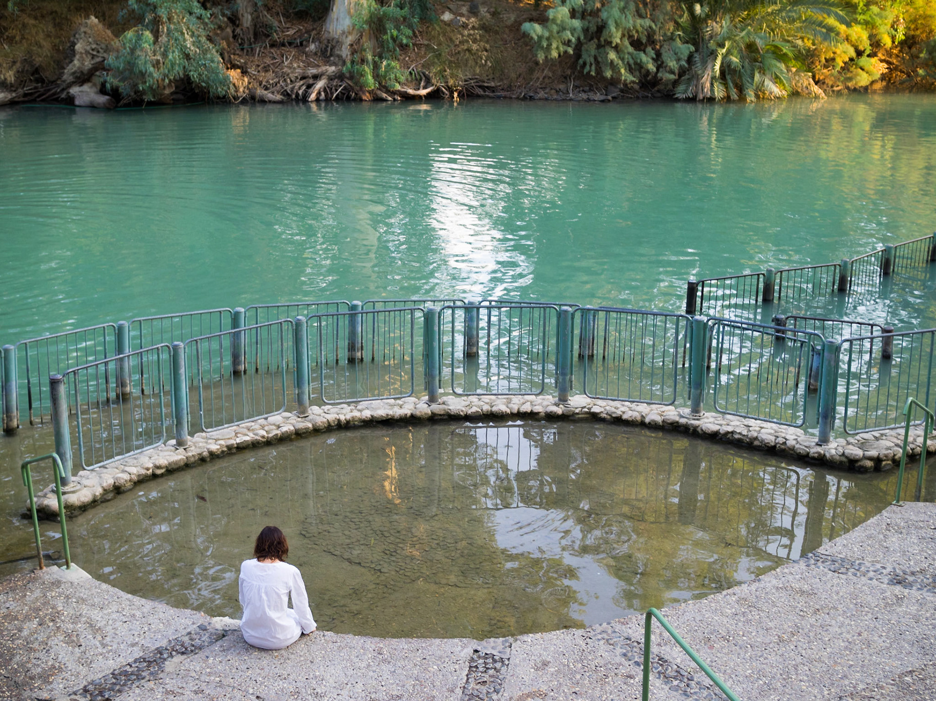 Christian woman seated in silence at the Yardenit baptismal site in Jordan river