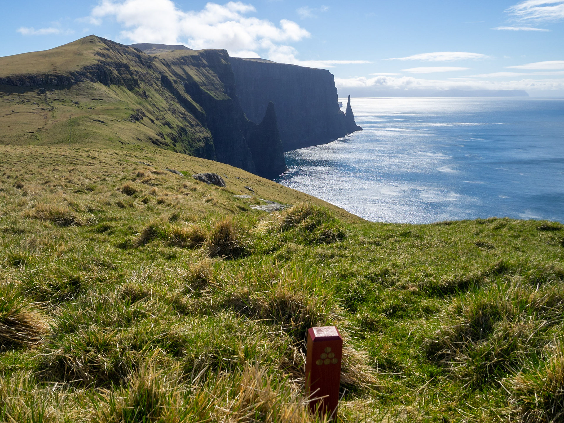 Hiking path sign in the grass atop the cliffs of Gleðin