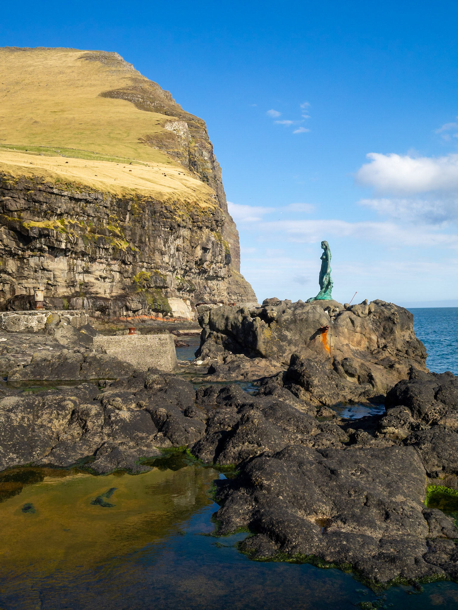 Kópakonan, the seal woman, statue over the rocks by the cliffs of Kalsoy coastline