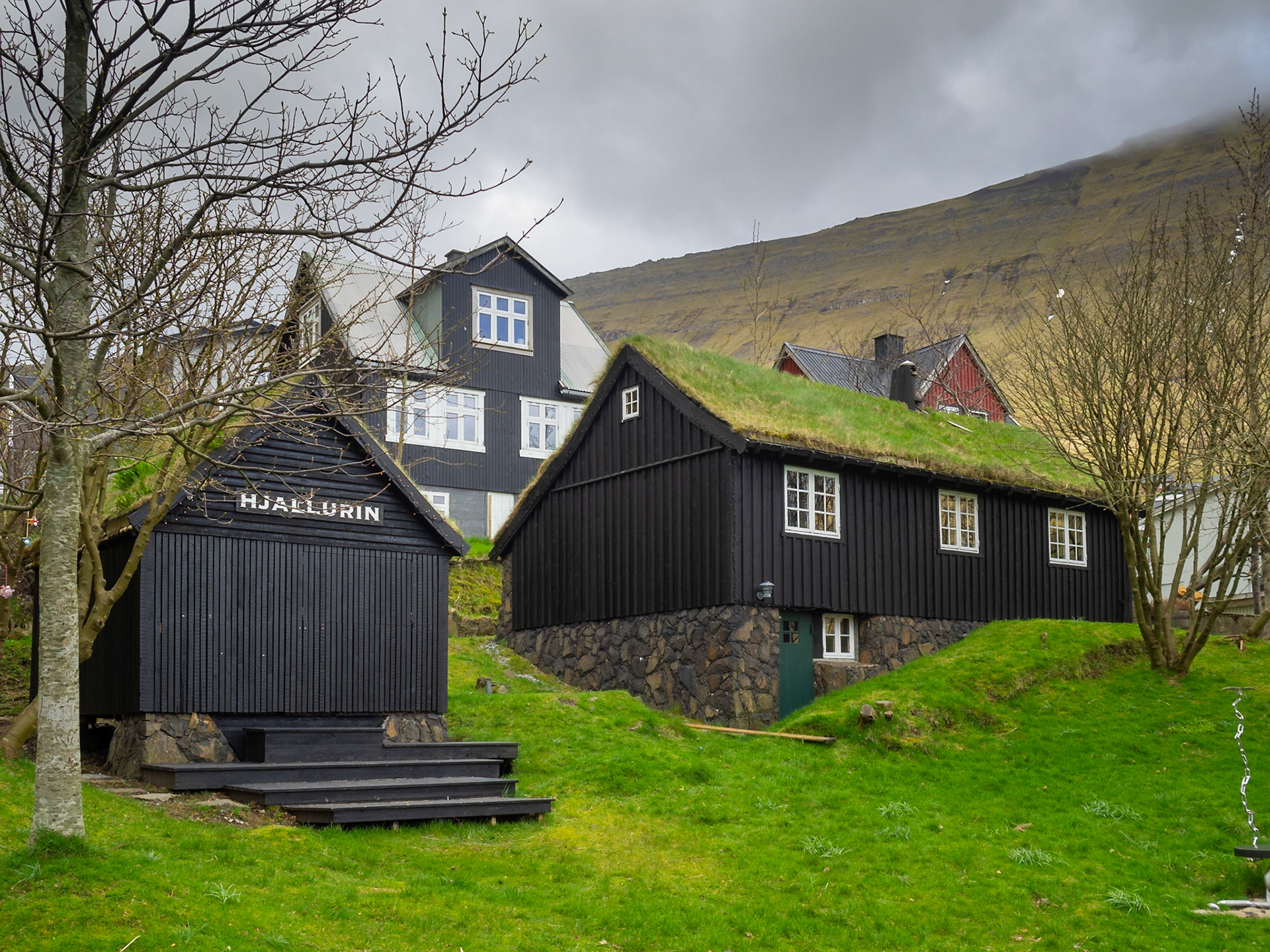 Traditional houses with black tared timber walls and turf roof in Fuglafjørður