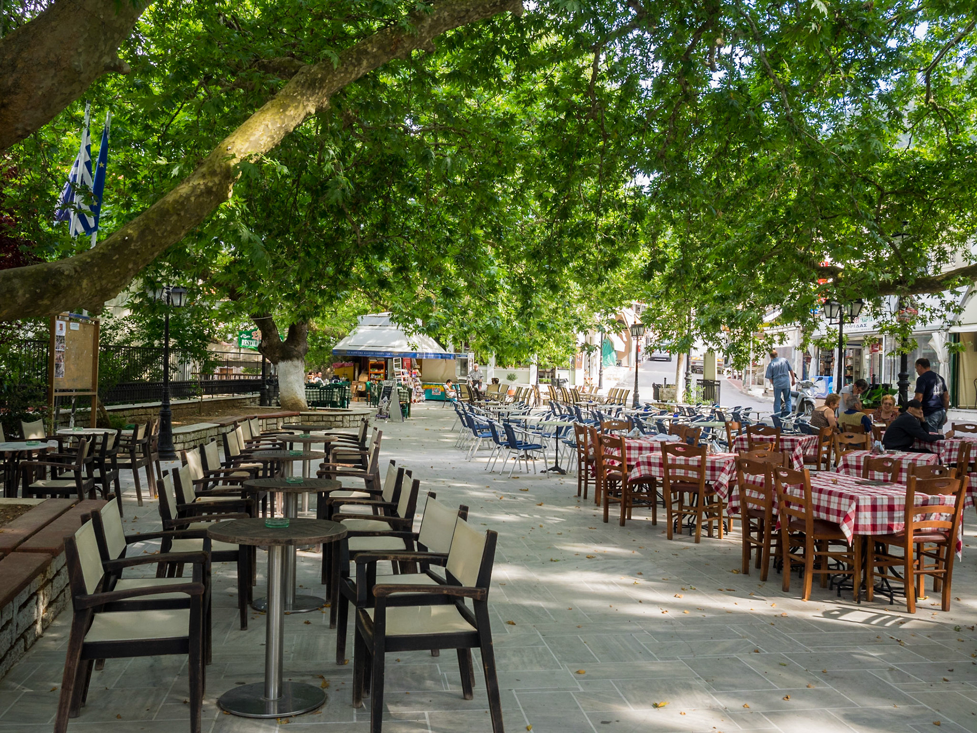 Restaurant tables under a tree shade in Karya main square