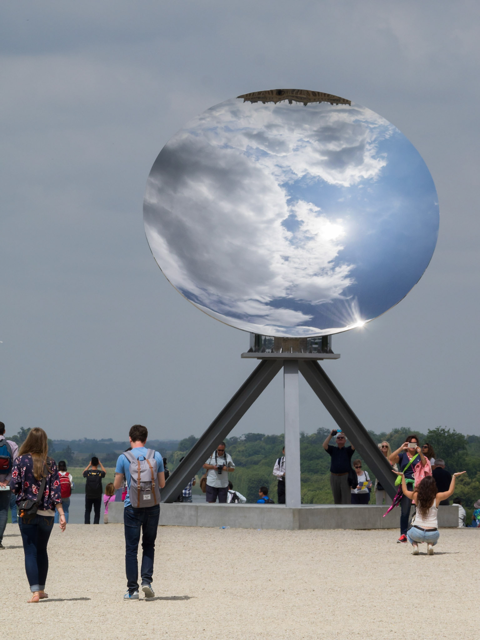 Versailles palace visitors around Anish Kapoor Sky Mirror sculpture installation at the palace gardens