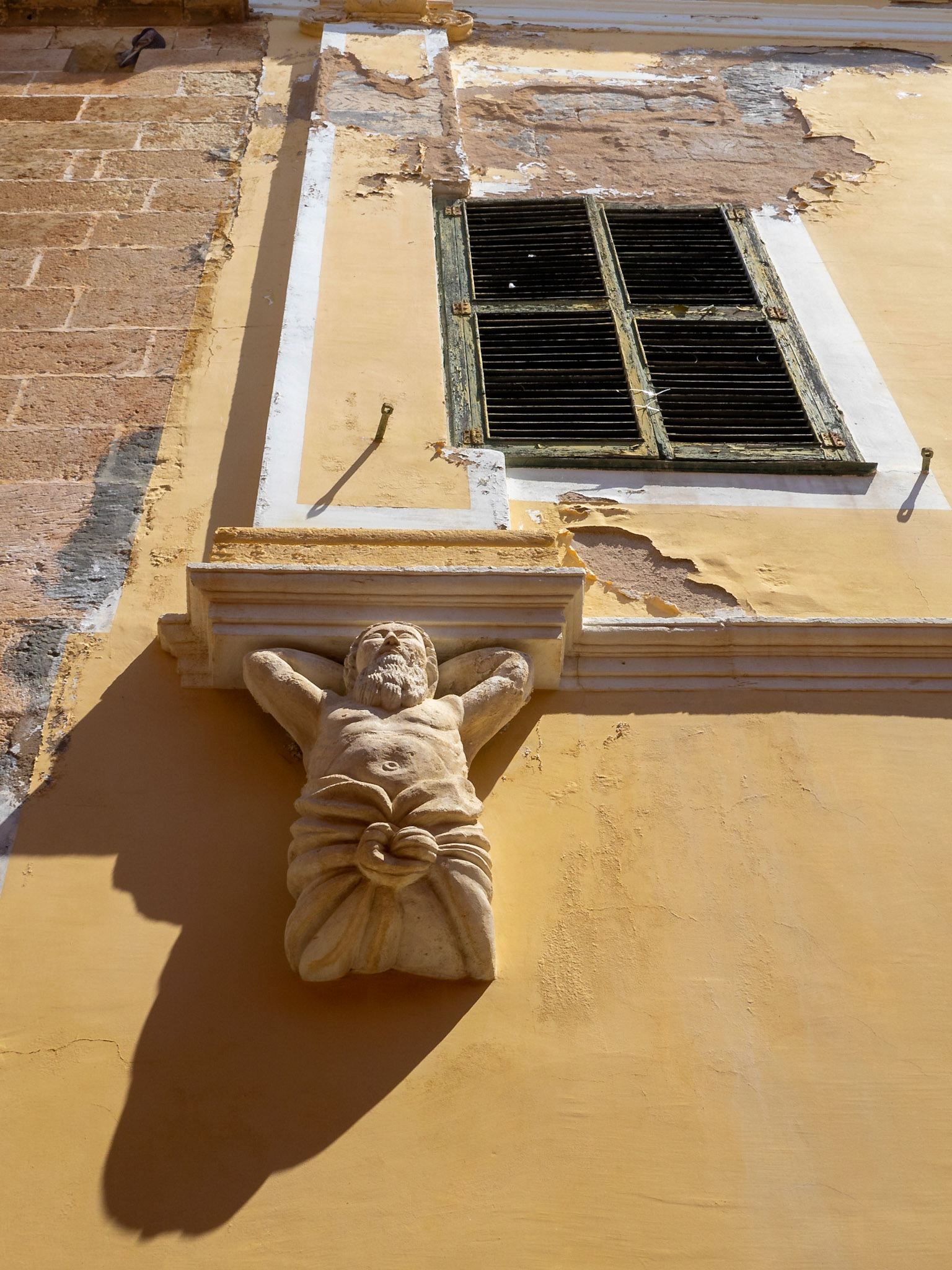 Detail of building stone carving depicting a man, Ciutadella
