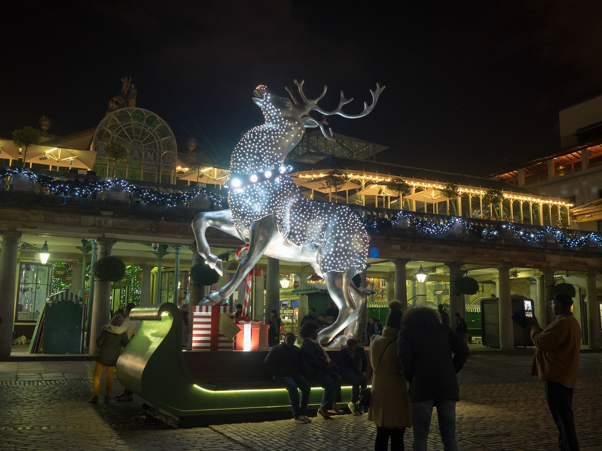 People taking pictures at night by the glowing reindeer of Covent Garden 2014  Christmas decorations