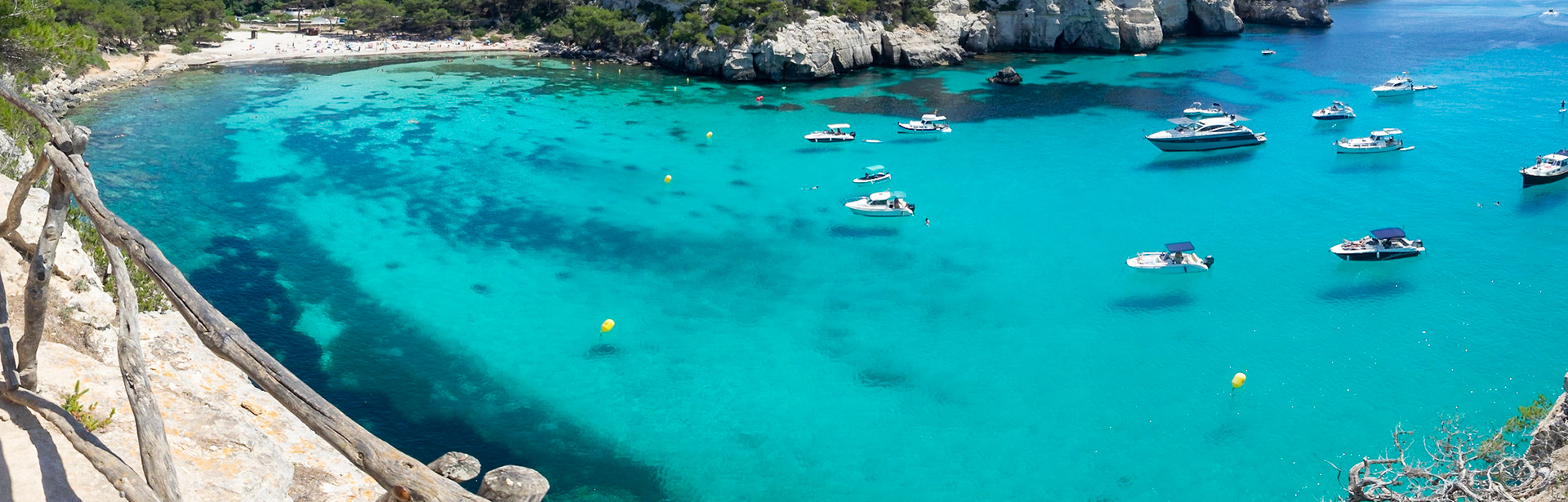 Boats floating in the cristal clear turquoise waters of Cala Macarella, Menorca