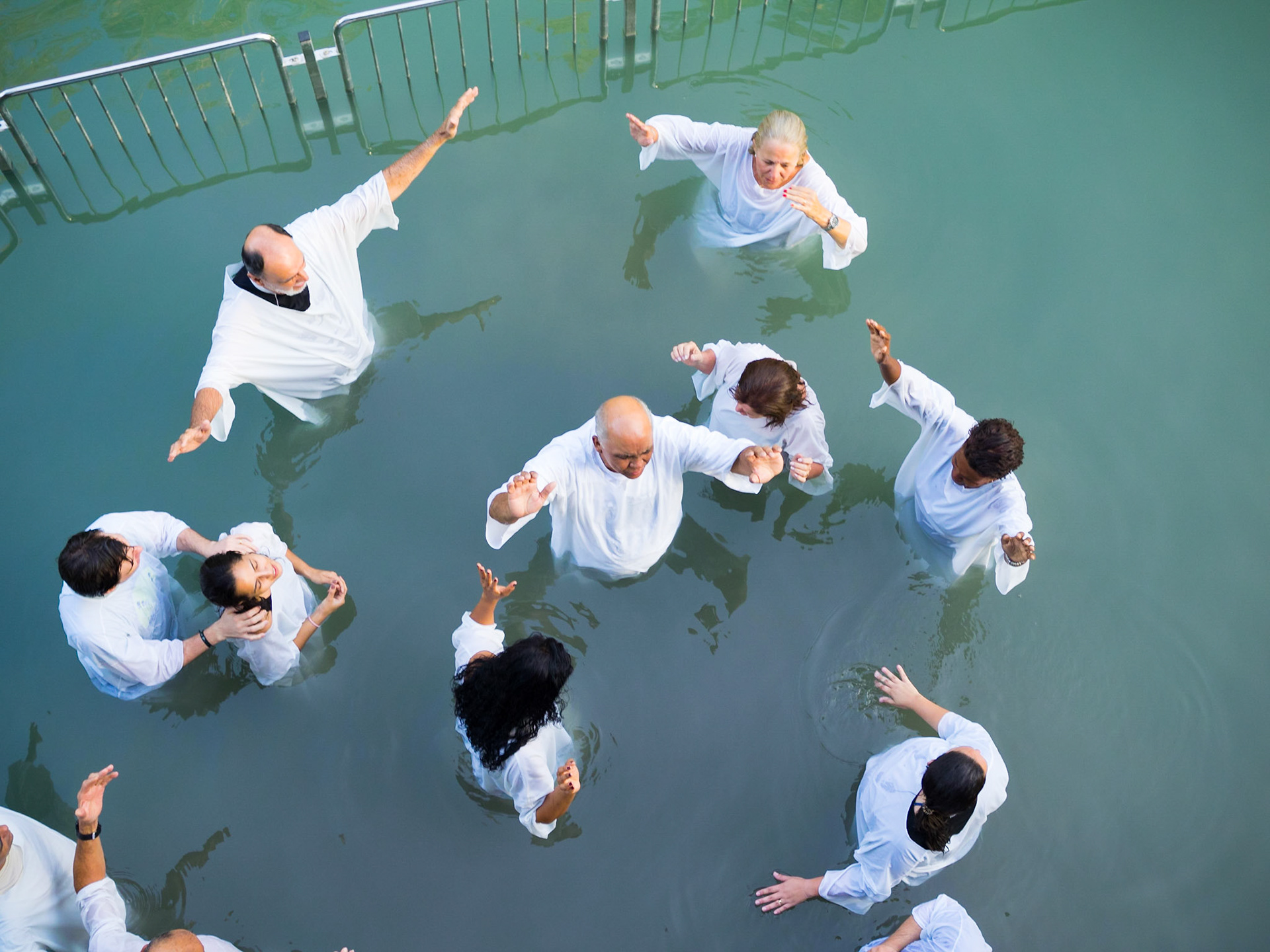 Christian group praying inside the water at the Yardenit baptismal site in Jordan river