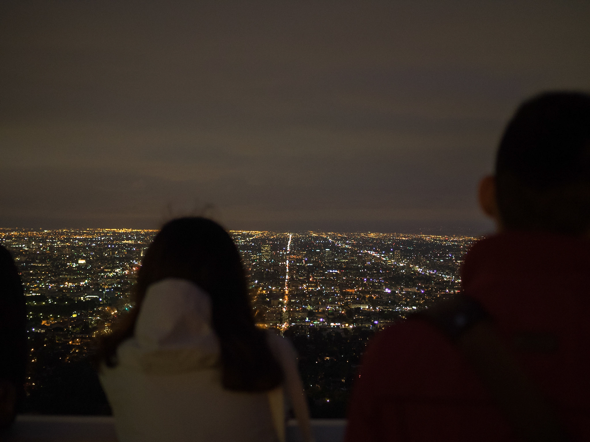 People looking over Los Angeles night lights from Griffith Observatory
