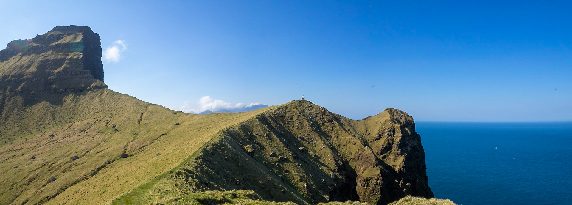 Panorama of Kallur lighthouse at the end of the hiking path, by the cliffs edge of north Kalsoy