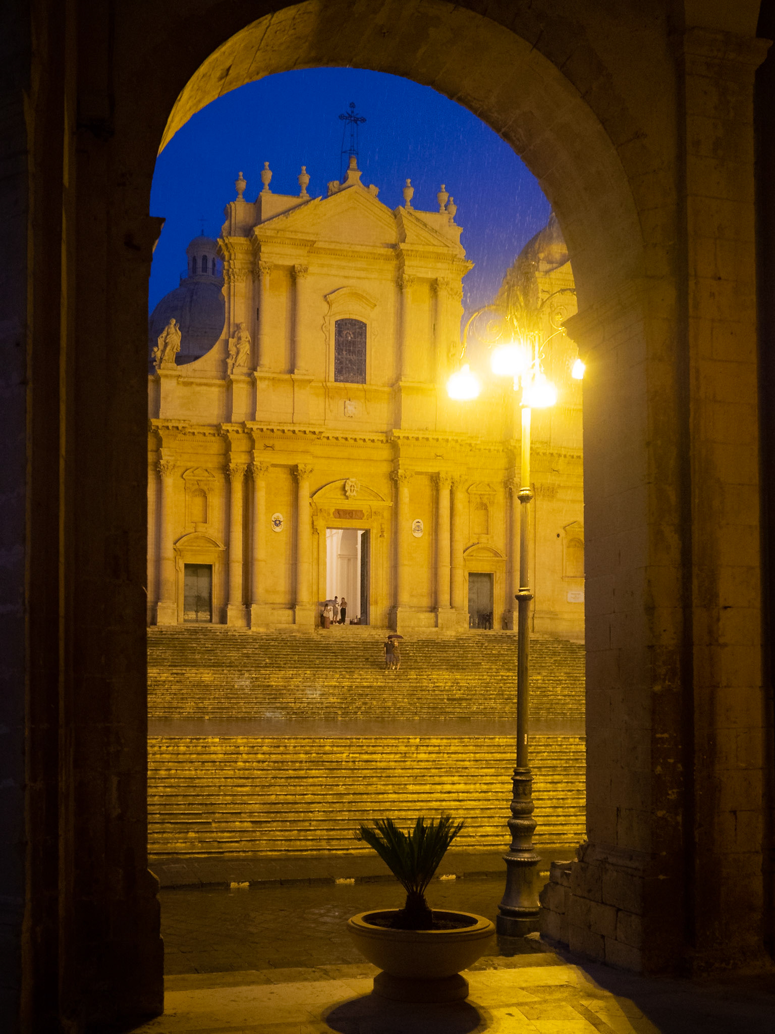 Duomo di Noto seen at night under the arches of the Palazzo Ducezio