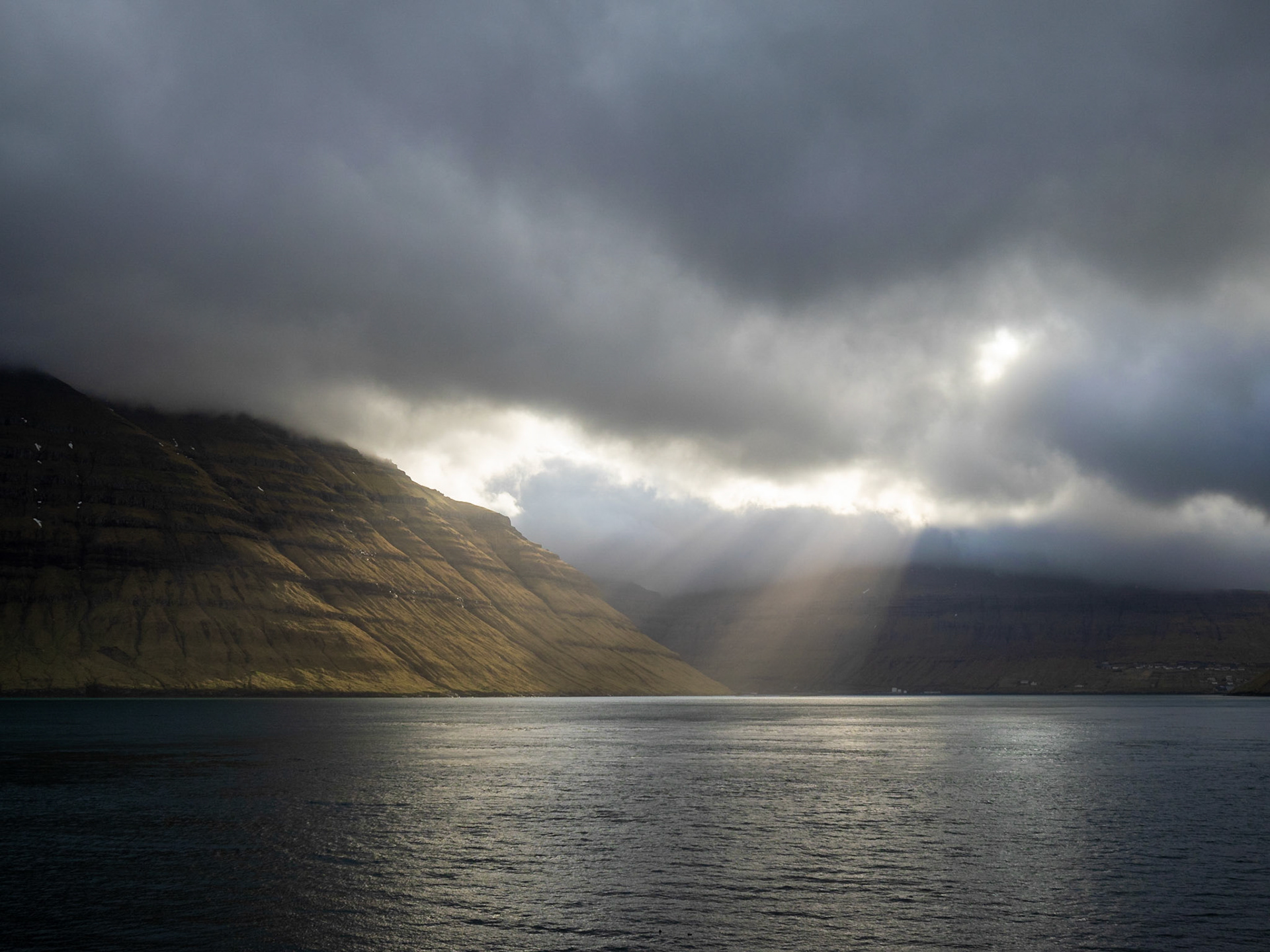 Kalsoyarfjørður fjord illuminated by the sunlight passing through the clouds