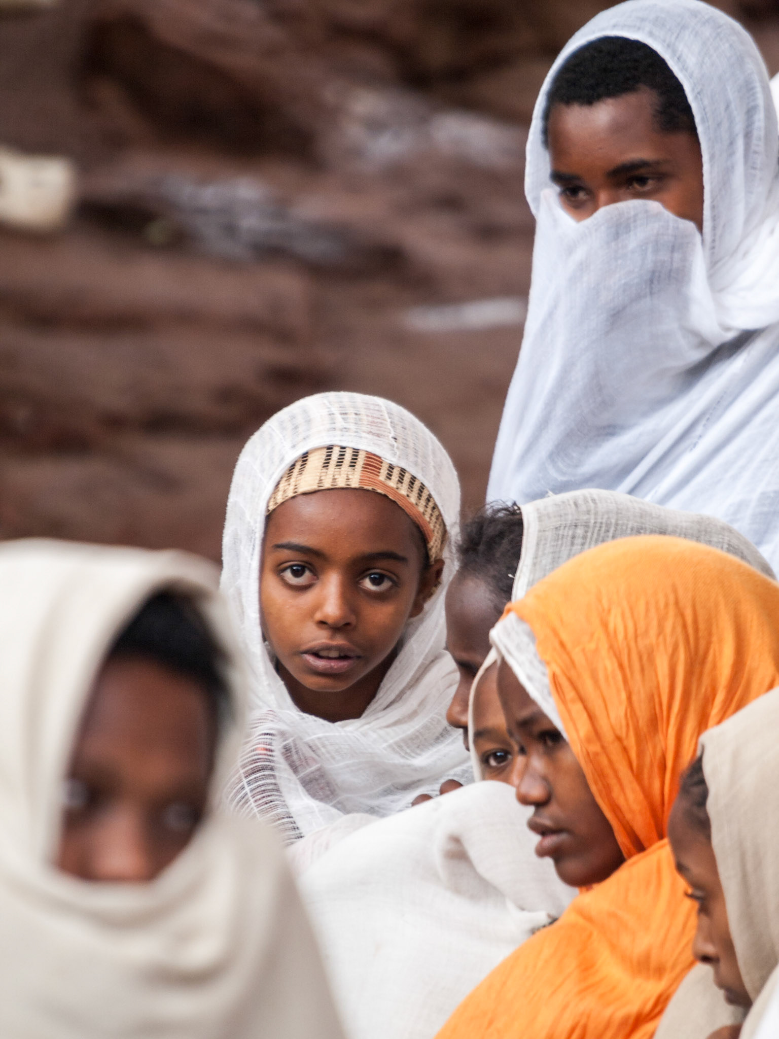 Young pilgrim girl with big eyes looks at camera outside church in Lalibela during Easter
