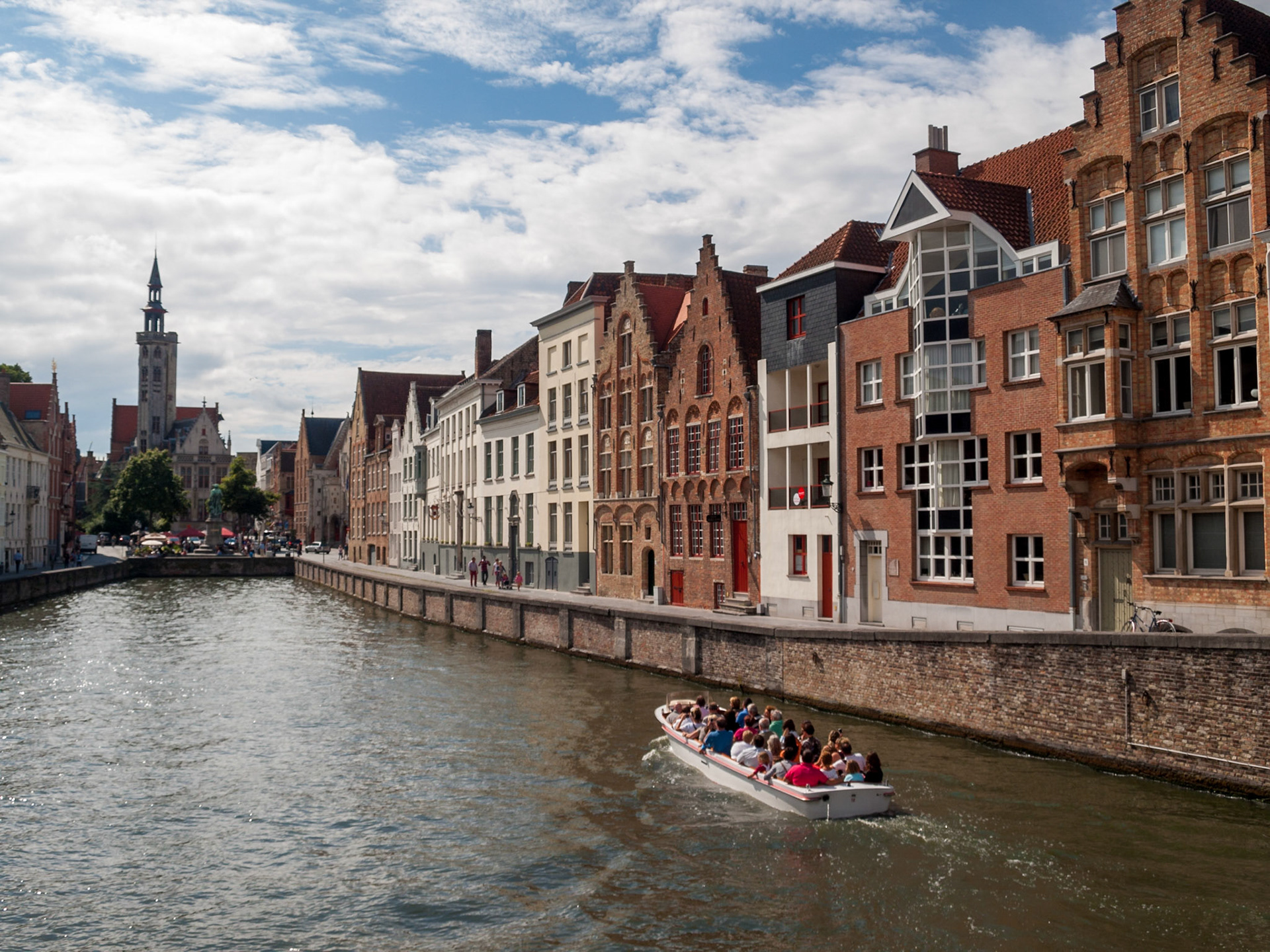 Bruges guilded canal houses and tourist boat